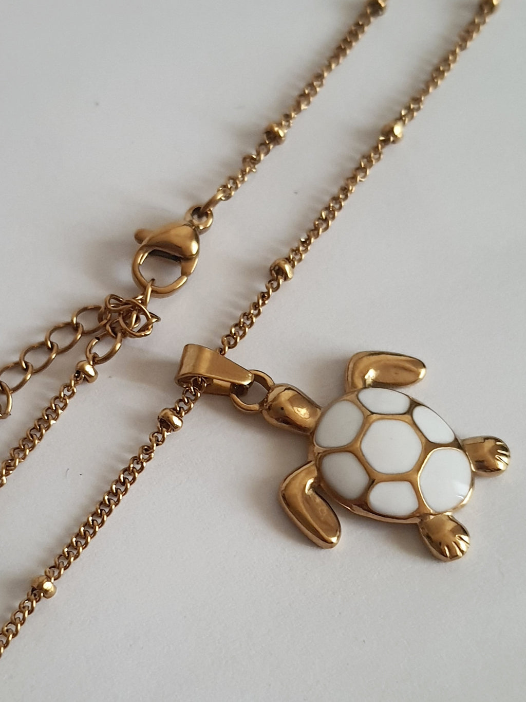 Naszyjnik złoty 40–45 cm ze stali nierdzewnej, zawieszka żółw z białą emalią na pancerzu, symboliczna i elegancka biżuteria, Rouge Bizu.#bizuteria #biżuteriapozłacana #stalnierdzewna #stalchirurgiczna #platerowane18k #wodoodporne #hipoalergiczne #retro #vintage #złotynaszyjnik #rougebizu