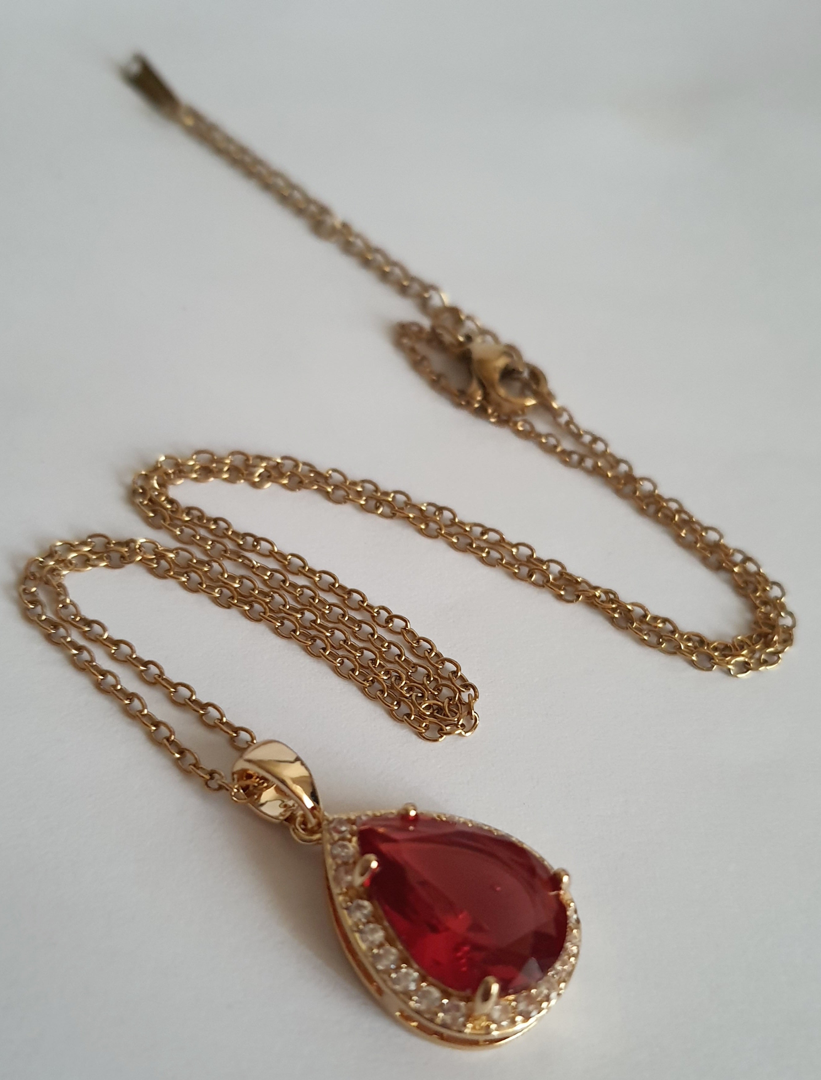 Naszyjnik złoty 41–47 cm ze stali nierdzewnej, zawieszka w kształcie łezki z rubinowym kryształem otoczonym cyrkoniami, Rouge Bizu.#bizuteria #biżuteriapozłacana #stalnierdzewna #stalchirurgiczna #platerowane18k #wodoodporne #hipoalergiczne #retro #vintage #złotynaszyjnik #rougebizu