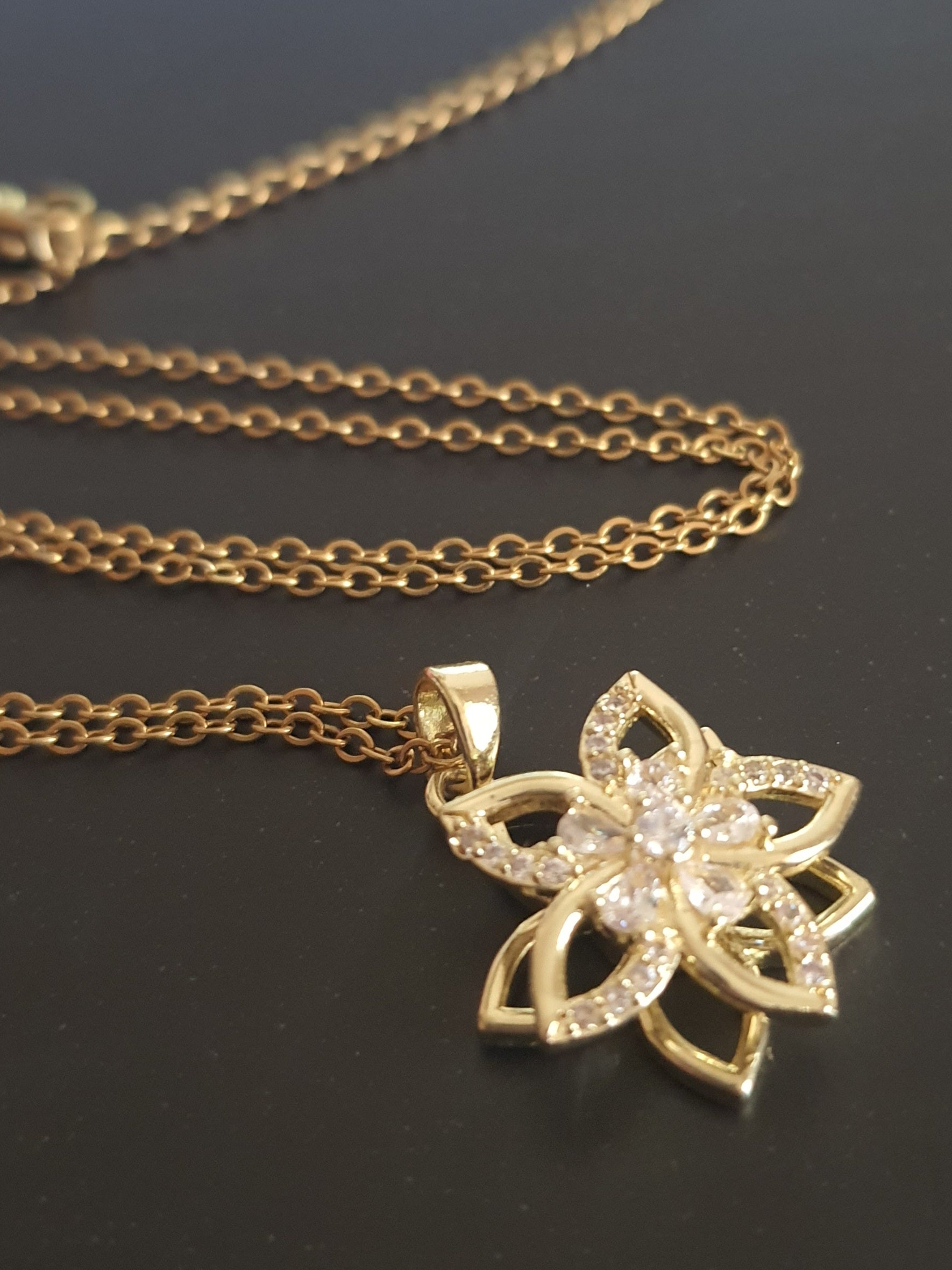 Złoty naszyjnik ze stali chirurgicznej z zawieszką w kształcie kwiatowej rozety wysadzanej cyrkoniami. Regulowana długość 45–50 cm. Stal chirurgiczna, stal nierdzewna, wodoodporne, hipoalergiczne, jakość premium. RougeBizu.