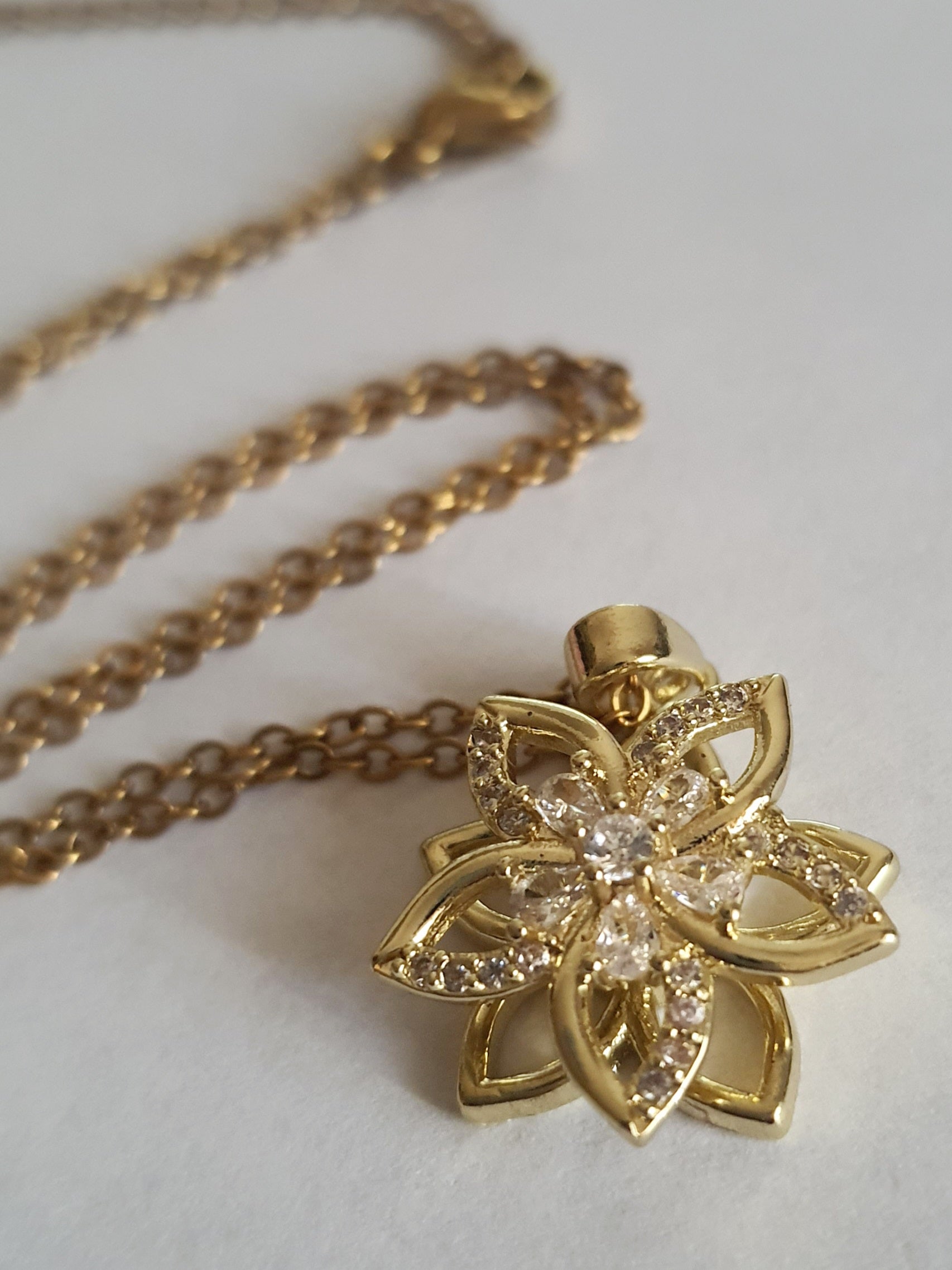 Złoty naszyjnik ze stali chirurgicznej z zawieszką w kształcie kwiatowej rozety wysadzanej cyrkoniami. Regulowana długość 45–50 cm. Stal chirurgiczna, stal nierdzewna, wodoodporne, hipoalergiczne, jakość premium. RougeBizu.