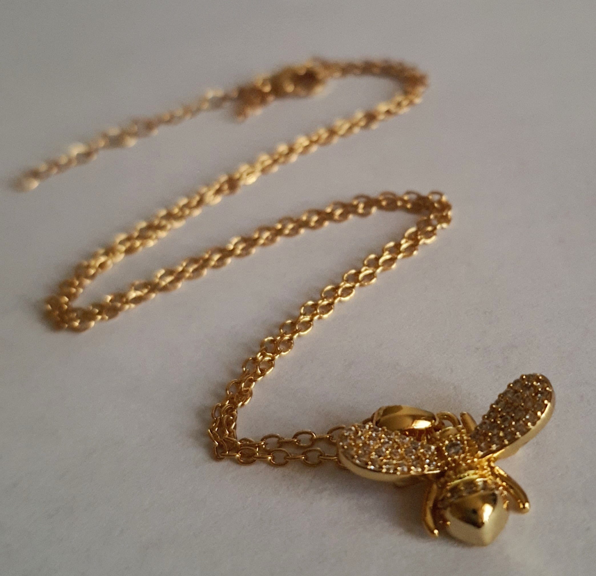 Złoty naszyjnik ze stali chirurgicznej z zawieszką w kształcie pszczółki wysadzanej cyrkoniami. Regulowana długość 40–45 cm. Stal chirurgiczna, stal nierdzewna, wodoodporne, hipoalergiczne, jakość premium. RougeBizu.