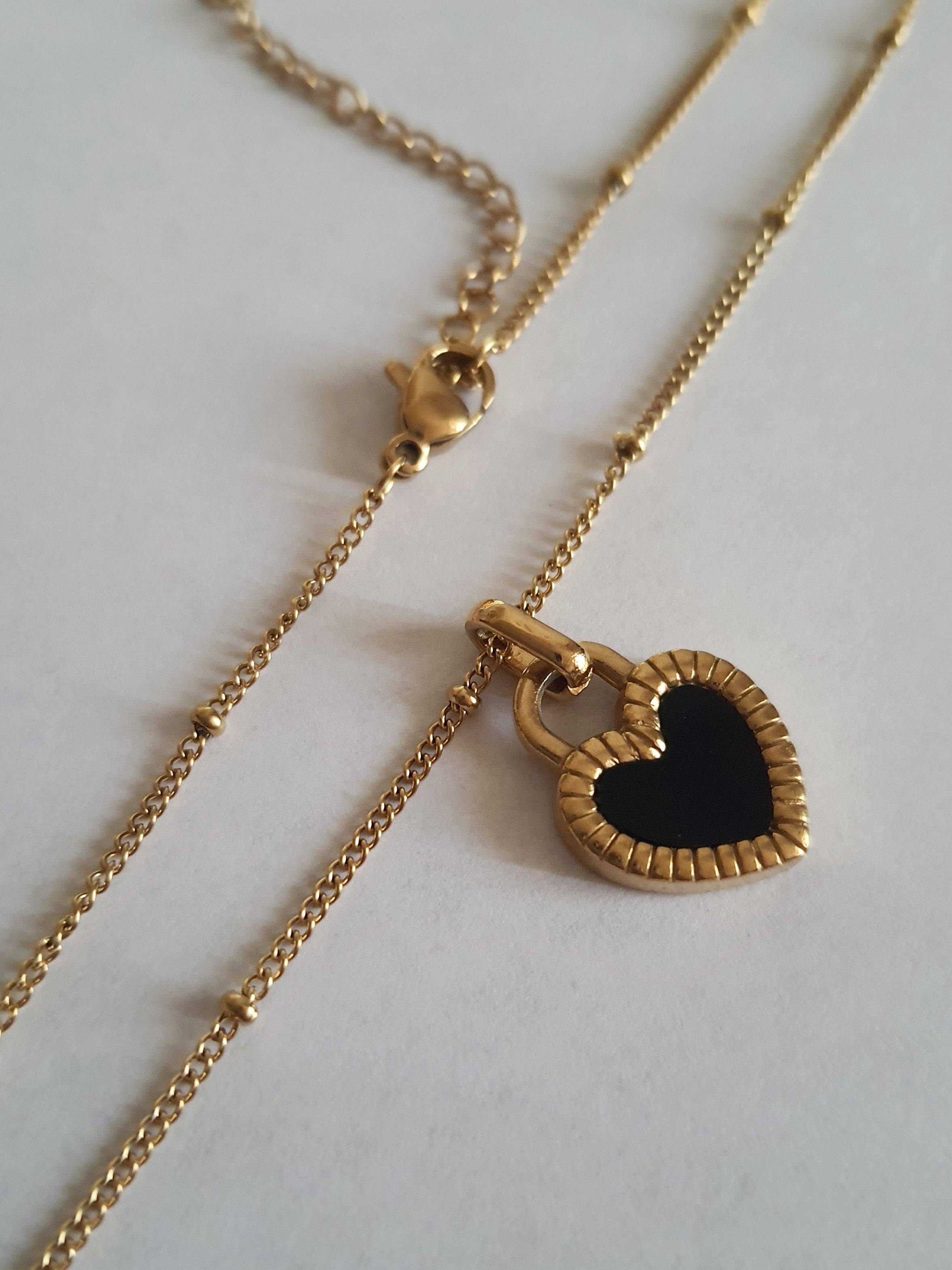 Złoty naszyjnik ze stali chirurgicznej z dwustronnym sercem – czarna i biała emalia. Regulowana długość 45–50 cm. Stal chirurgiczna, stal nierdzewna, wodoodporne, hipoalergiczne, jakość premium. RougeBizu.