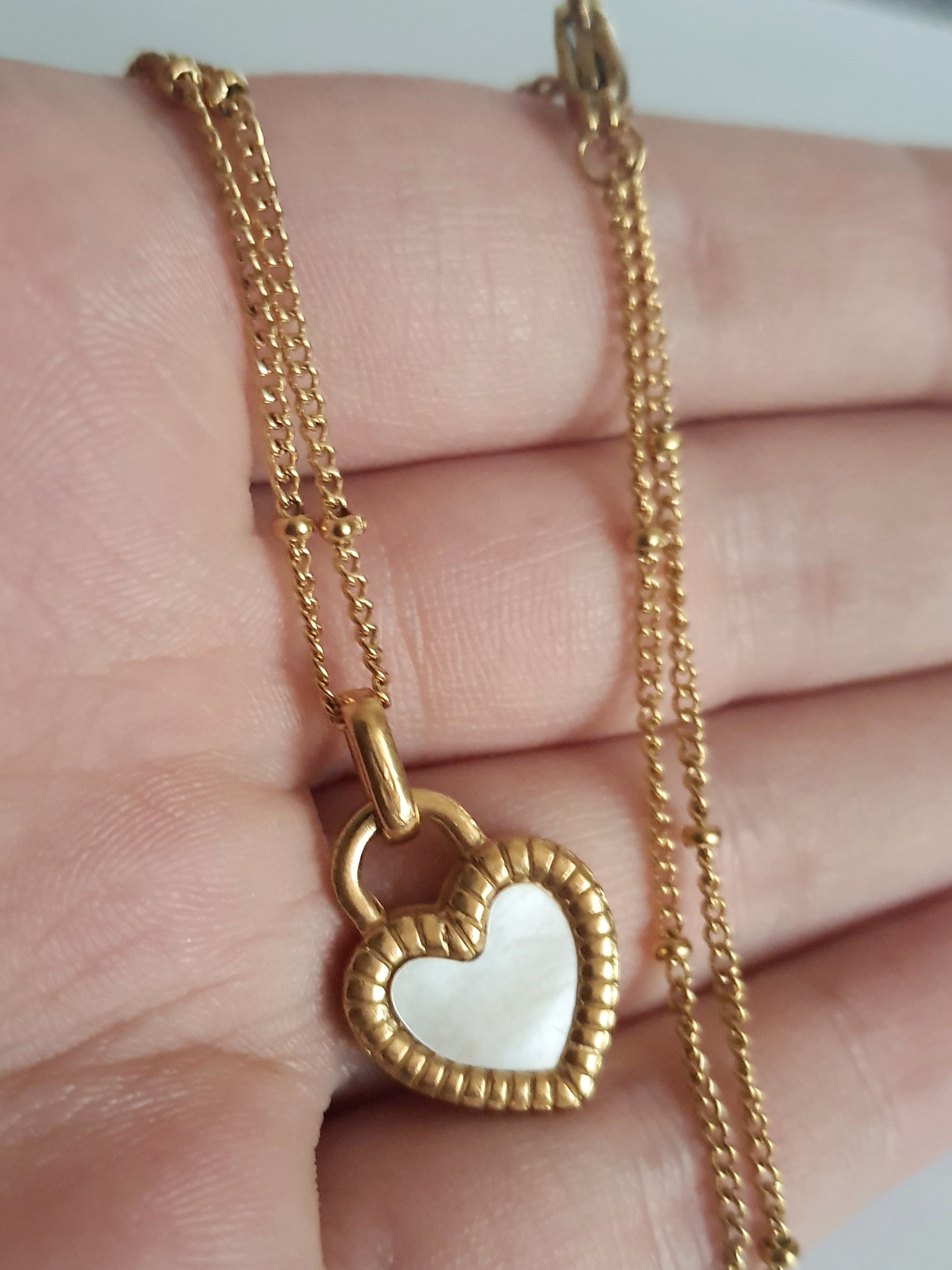 Złoty naszyjnik ze stali chirurgicznej z dwustronnym sercem – czarna i biała emalia. Regulowana długość 45–50 cm. Stal chirurgiczna, stal nierdzewna, wodoodporne, hipoalergiczne, jakość premium. RougeBizu.