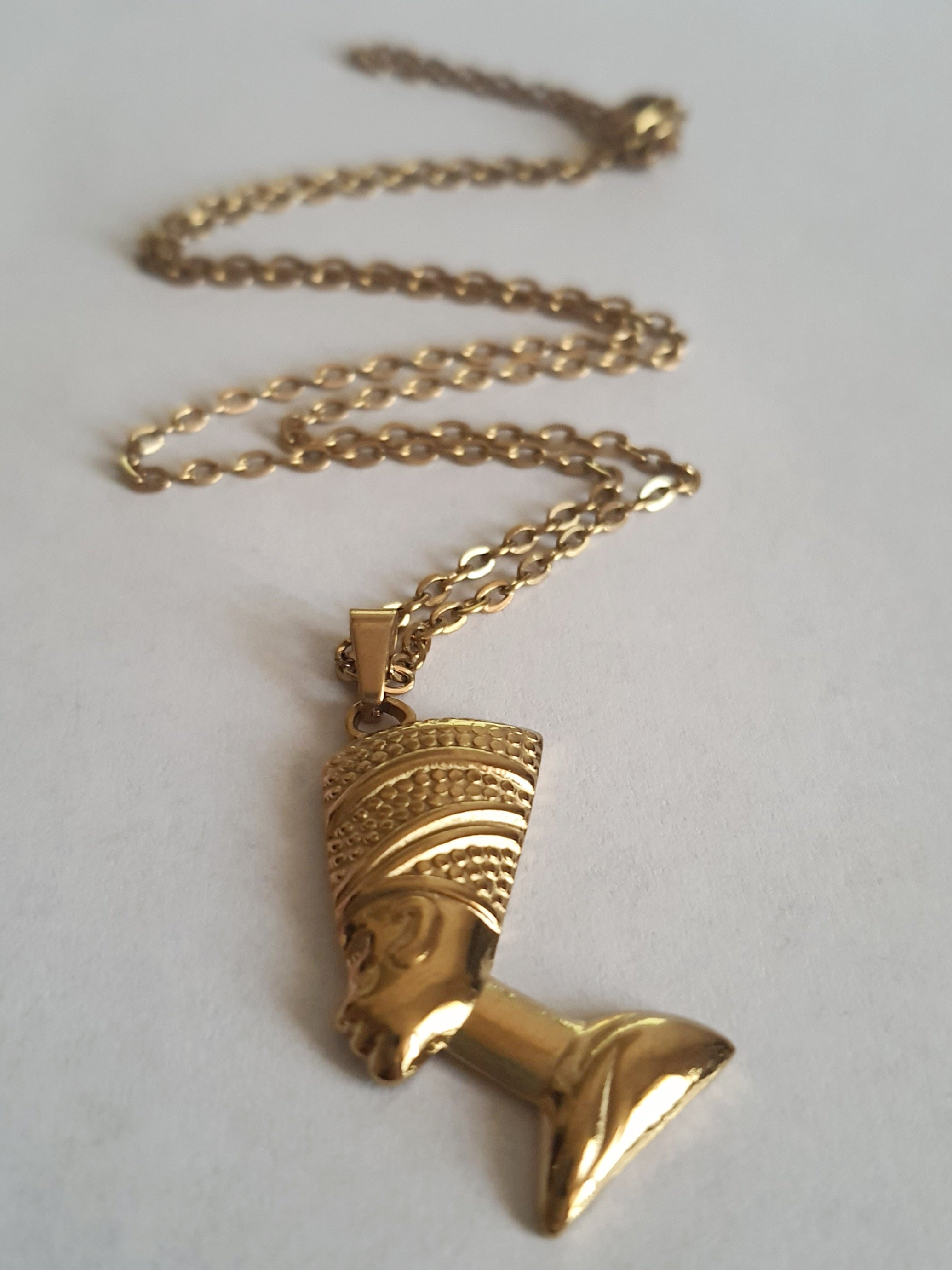 Złoty naszyjnik ze stali chirurgicznej z zawieszką w kształcie popiersia królowej Nefretete. Długość łańcuszka 50 cm. Stal chirurgiczna, stal nierdzewna, wodoodporne, hipoalergiczne, jakość premium. RougeBizu.