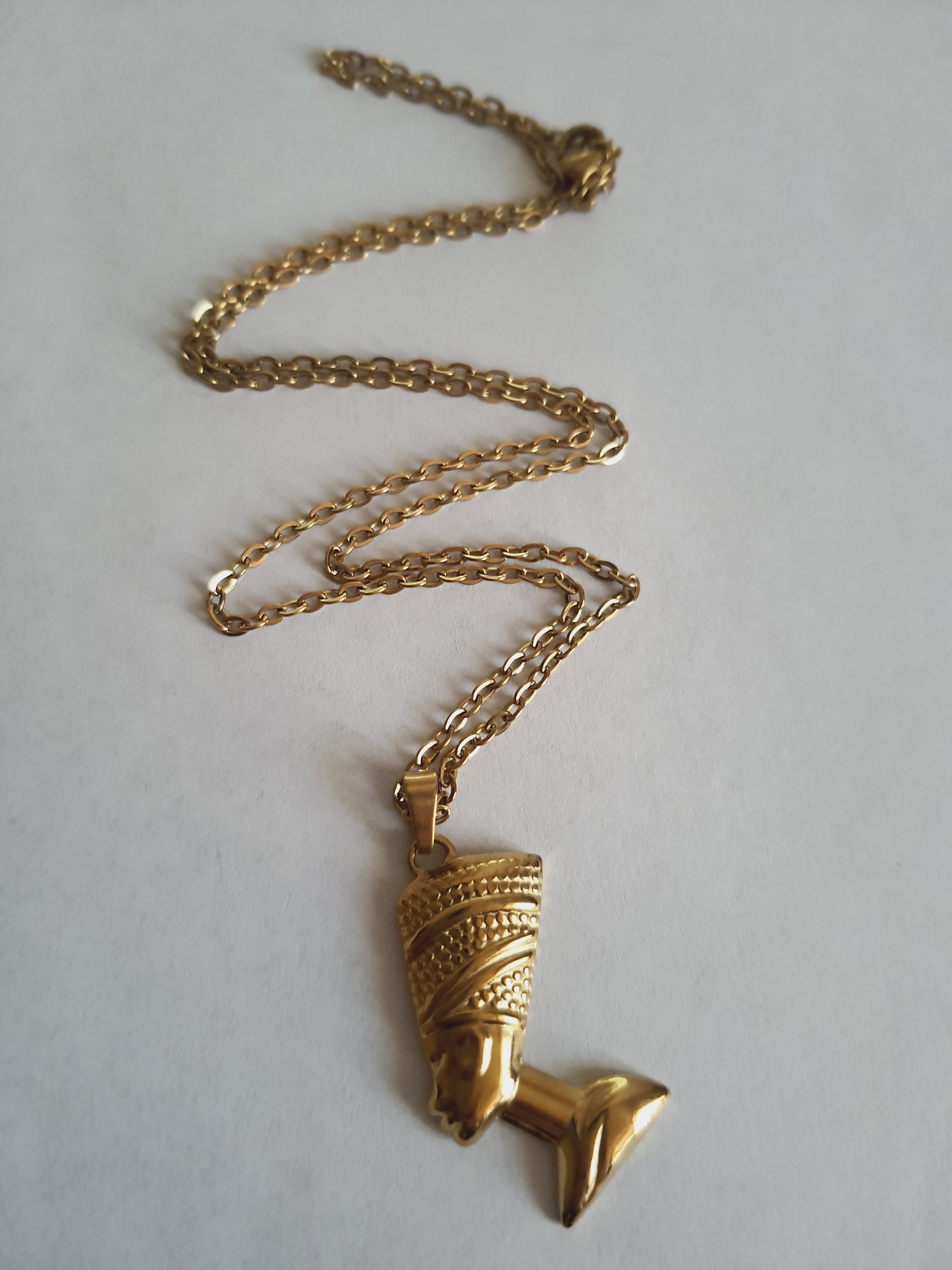 Złoty naszyjnik ze stali chirurgicznej z zawieszką w kształcie popiersia królowej Nefretete. Długość łańcuszka 50 cm. Stal chirurgiczna, stal nierdzewna, wodoodporne, hipoalergiczne, jakość premium. RougeBizu.