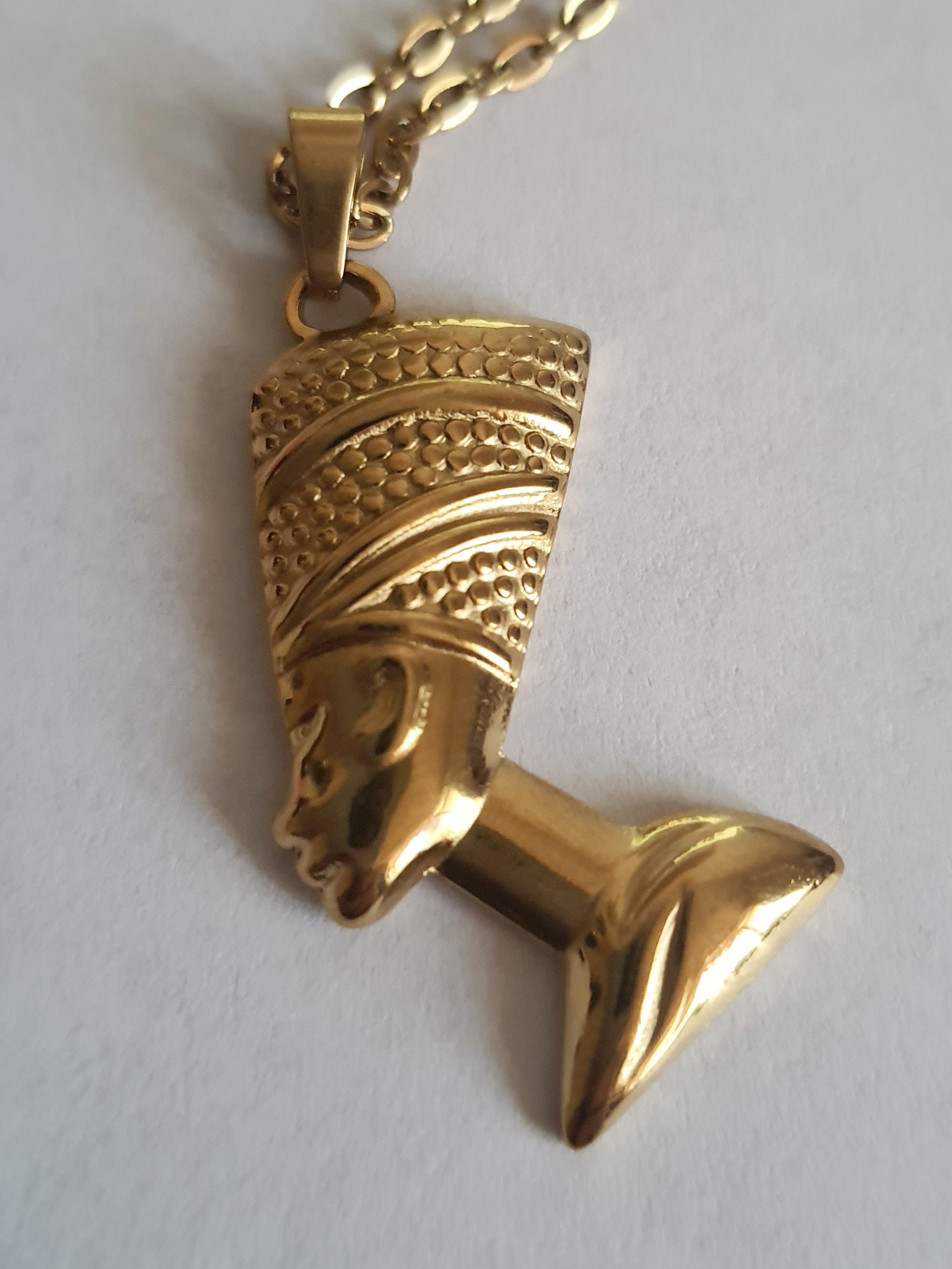 Złoty naszyjnik ze stali chirurgicznej z zawieszką w kształcie popiersia królowej Nefretete. Długość łańcuszka 50 cm. Stal chirurgiczna, stal nierdzewna, wodoodporne, hipoalergiczne, jakość premium. RougeBizu.