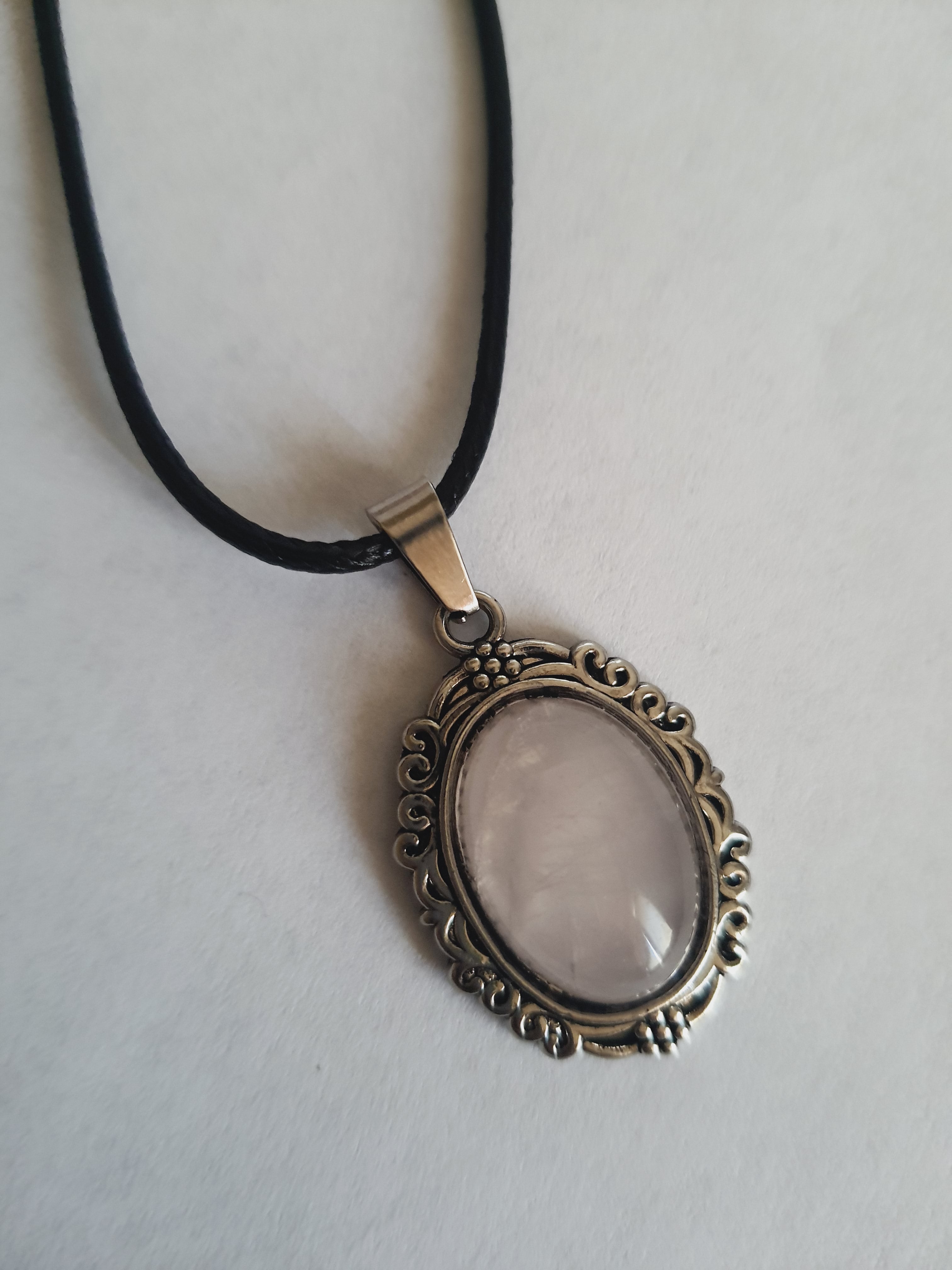 Naszyjnik vintage ze stali chirurgicznej z syntetycznym różowym kwarcem w ozdobnej srebrzystej ramce. Czarny rzemyk, długość regulowana 45–50 cm. Stal chirurgiczna, stal nierdzewna, wodoodporne, hipoalergiczne, jakość premium. RougeBizu.