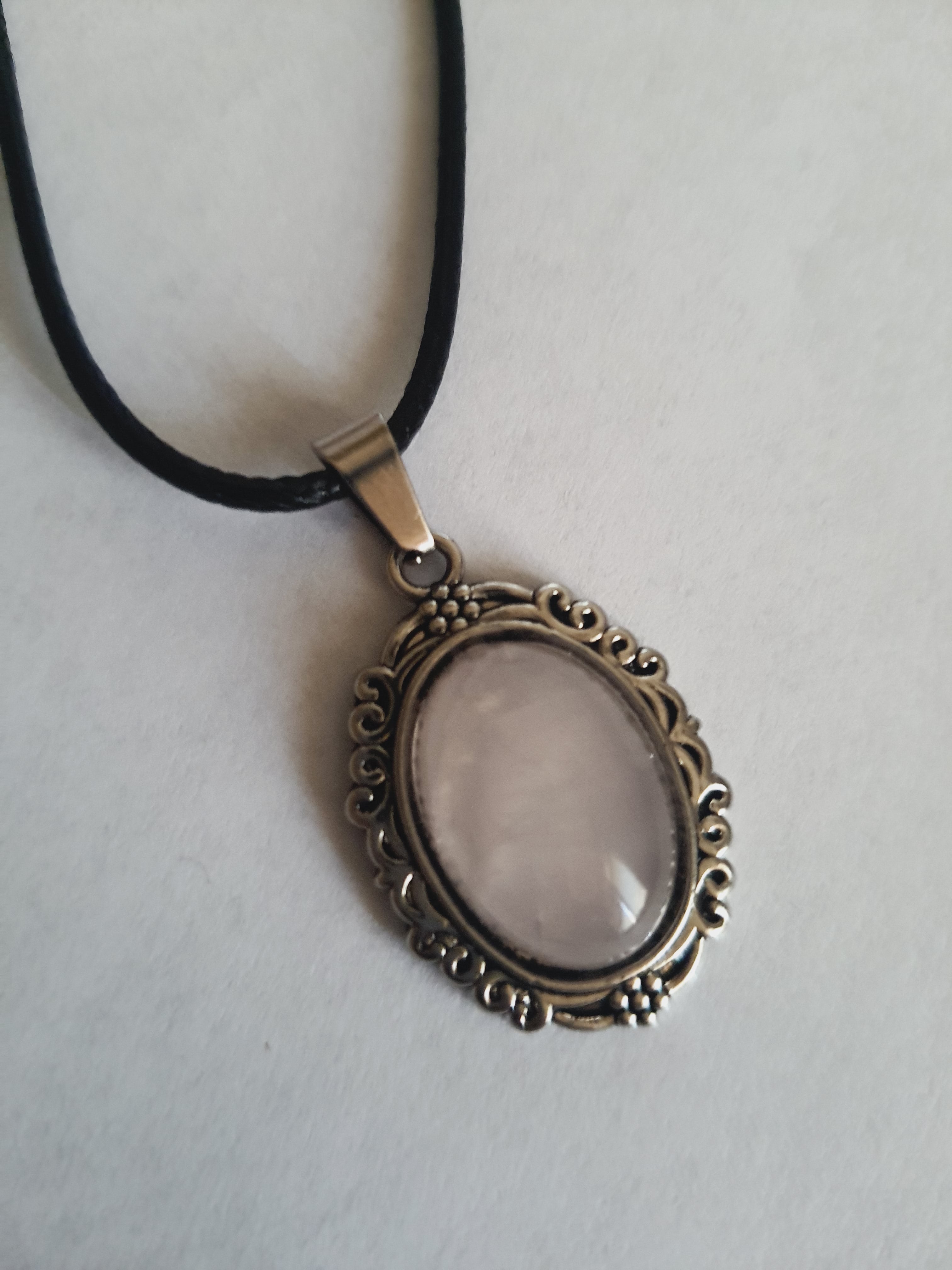 Naszyjnik vintage ze stali chirurgicznej z syntetycznym różowym kwarcem w ozdobnej srebrzystej ramce. Czarny rzemyk, długość regulowana 45–50 cm. Stal chirurgiczna, stal nierdzewna, wodoodporne, hipoalergiczne, jakość premium. RougeBizu.