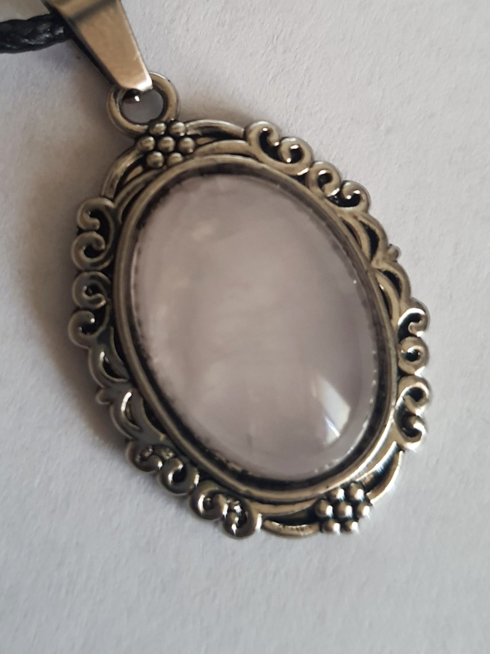 Naszyjnik vintage ze stali chirurgicznej z syntetycznym różowym kwarcem w ozdobnej srebrzystej ramce. Czarny rzemyk, długość regulowana 45–50 cm. Stal chirurgiczna, stal nierdzewna, wodoodporne, hipoalergiczne, jakość premium. RougeBizu.