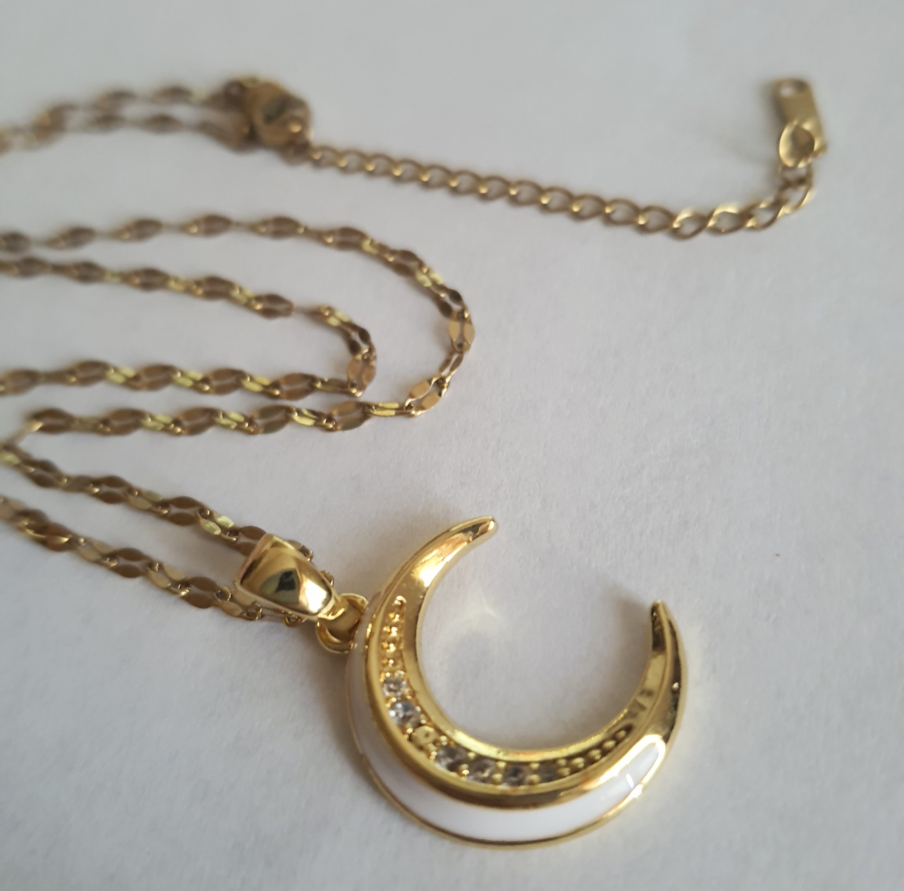 Złoty naszyjnik ze stali chirurgicznej z zawieszką w kształcie półksiężyca wysadzanego cyrkoniami. Regulowana długość 40–45 cm. Stal chirurgiczna, stal nierdzewna, wodoodporne, hipoalergiczne, jakość premium. RougeBizu.