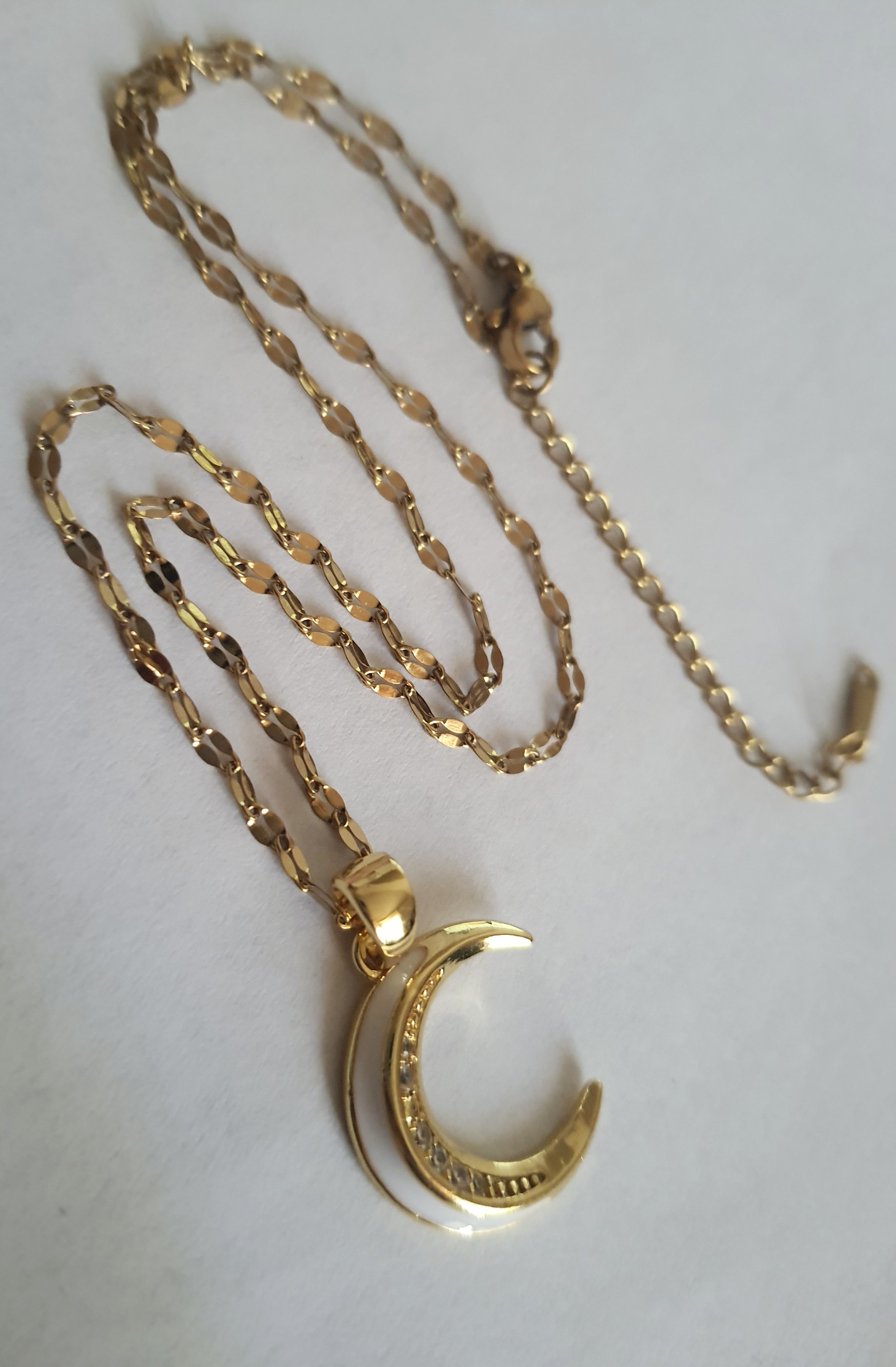 Złoty naszyjnik ze stali chirurgicznej z zawieszką w kształcie półksiężyca wysadzanego cyrkoniami. Regulowana długość 40–45 cm. Stal chirurgiczna, stal nierdzewna, wodoodporne, hipoalergiczne, jakość premium. RougeBizu.