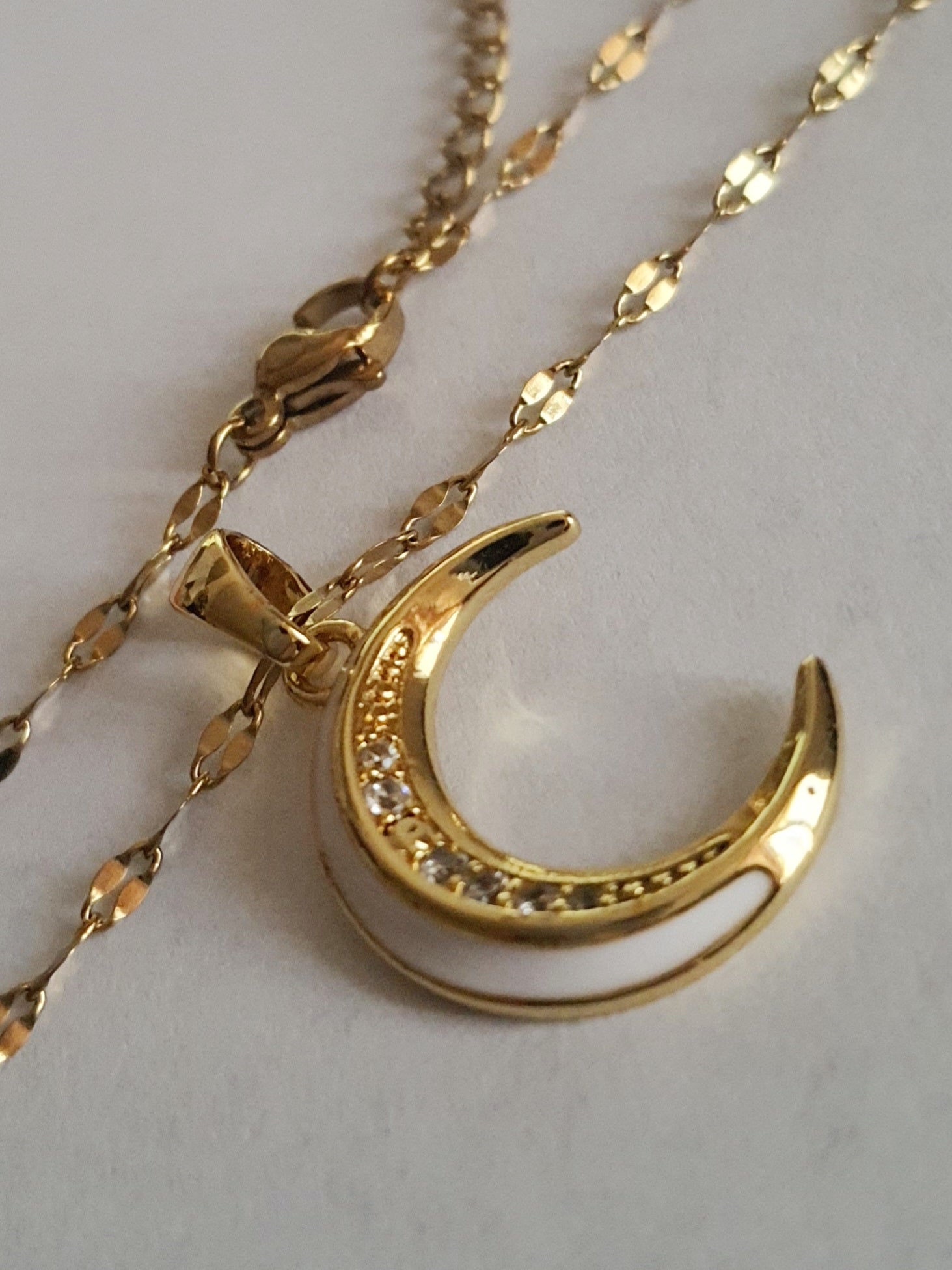 Złoty naszyjnik ze stali chirurgicznej z zawieszką w kształcie półksiężyca wysadzanego cyrkoniami. Regulowana długość 40–45 cm. Stal chirurgiczna, stal nierdzewna, wodoodporne, hipoalergiczne, jakość premium. RougeBizu.