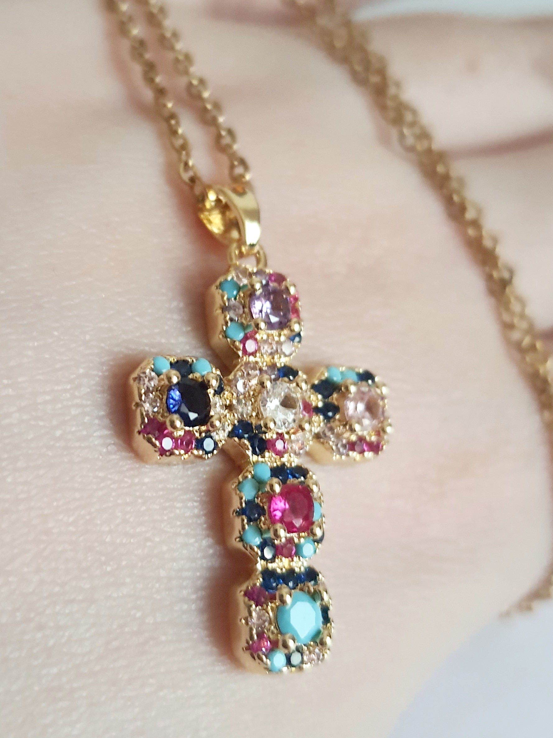 Złoty naszyjnik ze stali chirurgicznej z zawieszką w kształcie krzyża wysadzanego kolorowymi kryształami (czerwonymi, niebieskimi, fioletowymi, turkusowymi). Długość łańcuszka 50 cm. Stal chirurgiczna, stal nierdzewna, wodoodporne, hipoalergiczne, jakość premium. RougeBizu.