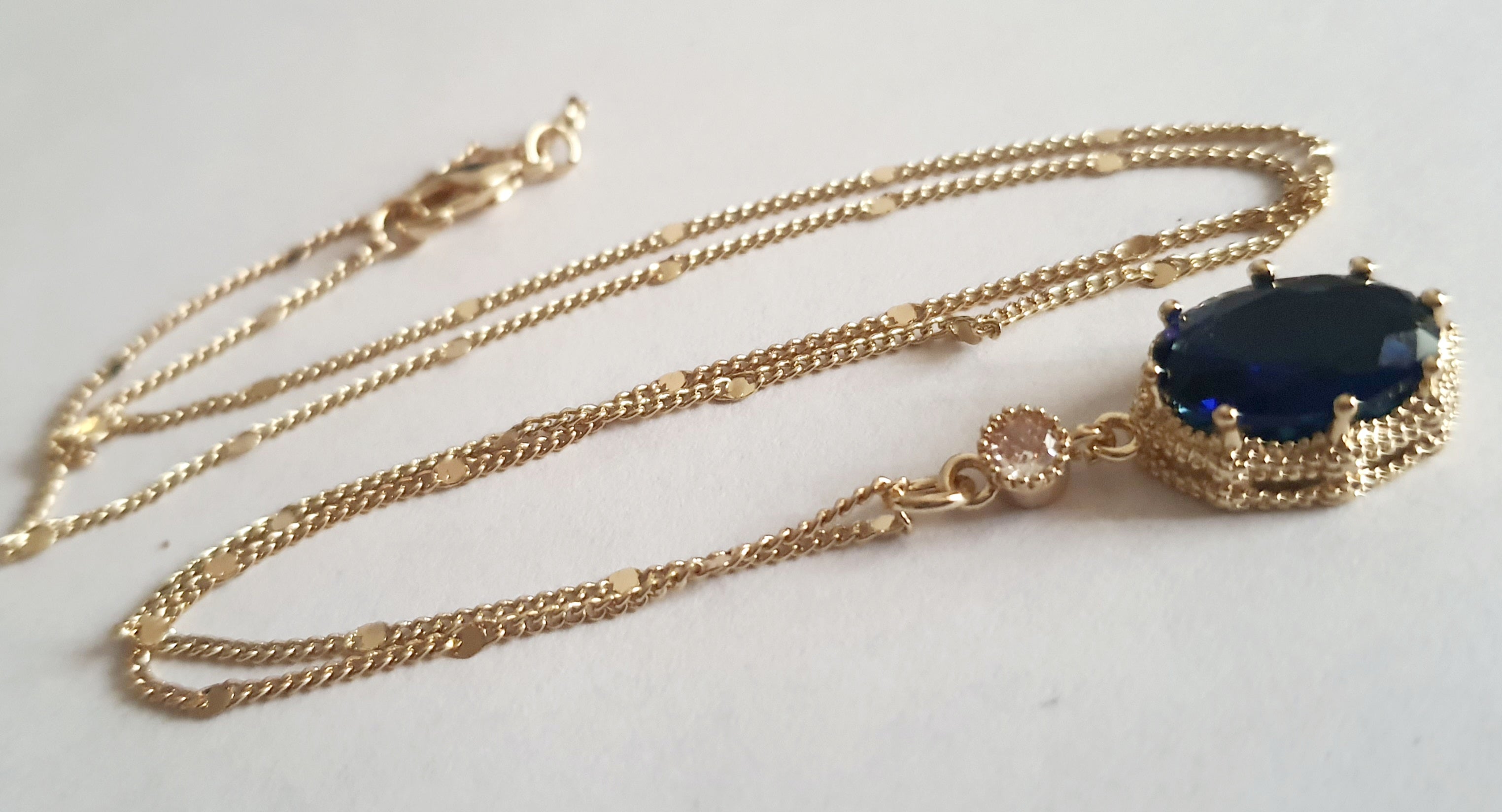 Złoty naszyjnik ze stali chirurgicznej z granatowym kamieniem w ozdobnej ramce i małą cyrkonią. Długość 47 cm. Stal chirurgiczna, stal nierdzewna, wodoodporne, hipoalergiczne, jakość premium. RougeBizu.