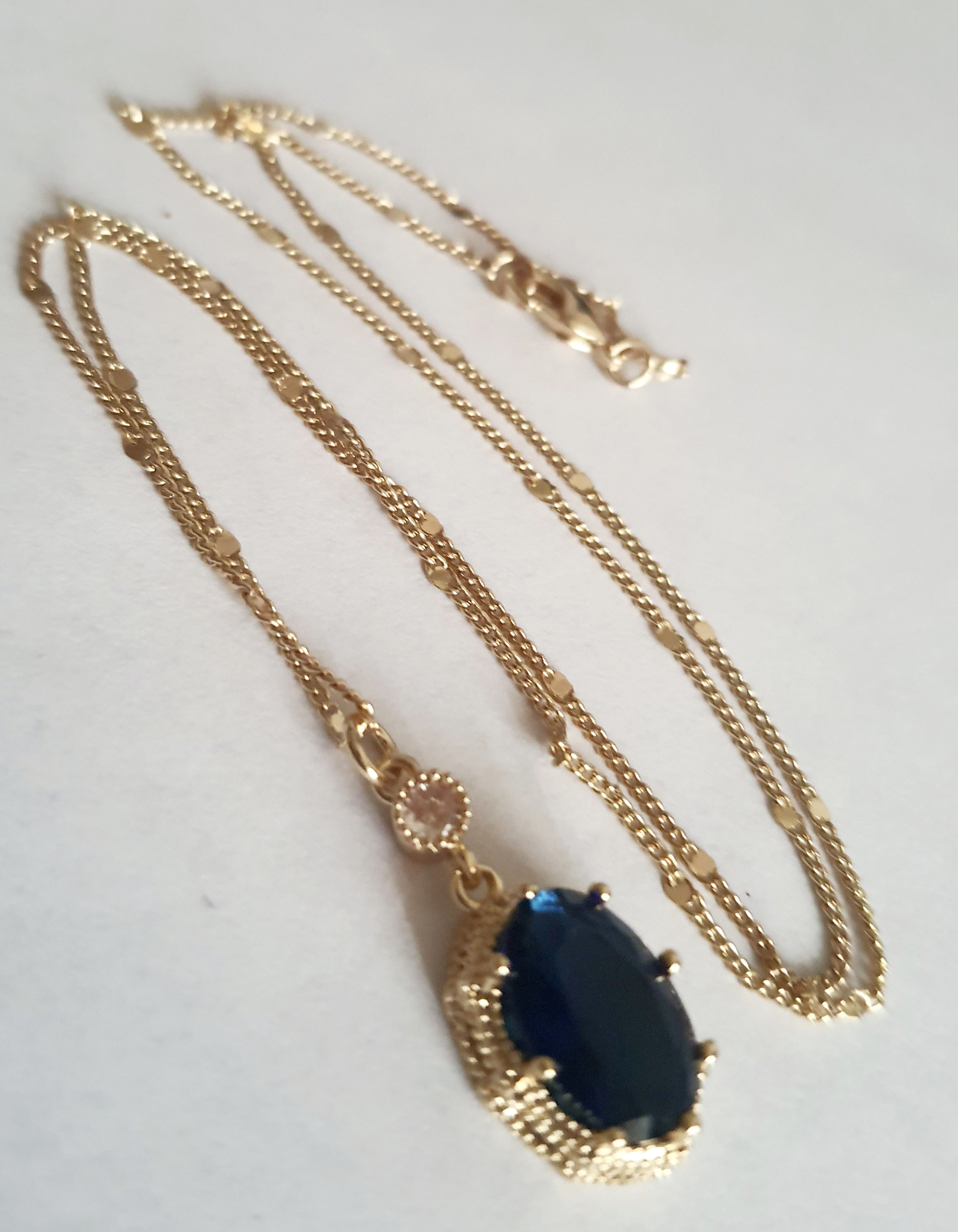 Złoty naszyjnik ze stali chirurgicznej z granatowym kamieniem w ozdobnej ramce i małą cyrkonią. Długość 47 cm. Stal chirurgiczna, stal nierdzewna, wodoodporne, hipoalergiczne, jakość premium. RougeBizu.