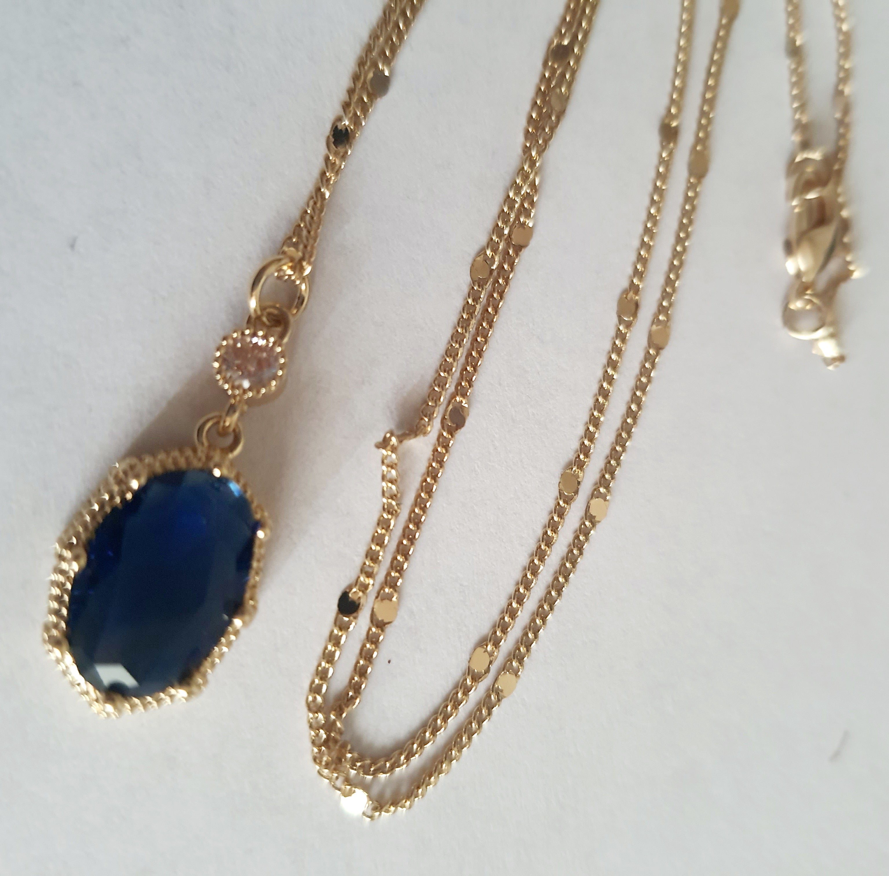 Złoty naszyjnik ze stali chirurgicznej z granatowym kamieniem w ozdobnej ramce i małą cyrkonią. Długość 47 cm. Stal chirurgiczna, stal nierdzewna, wodoodporne, hipoalergiczne, jakość premium. RougeBizu.