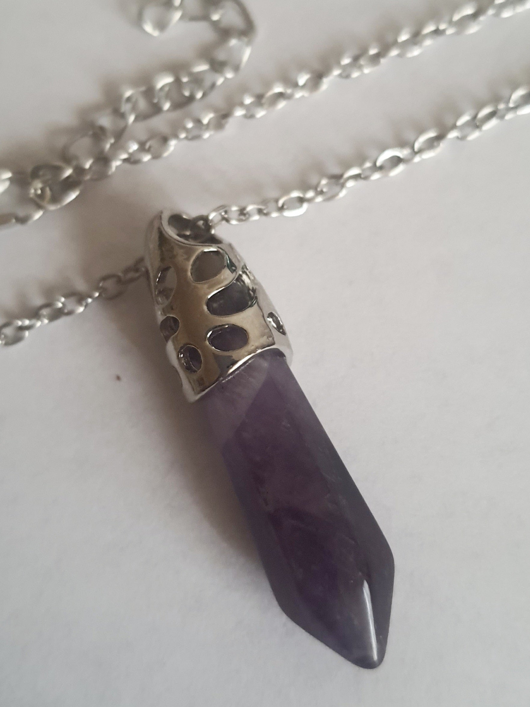 Srebrny naszyjnik ze stali chirurgicznej z zawieszką w postaci syntetycznego ametystu w kształcie szpica. Regulowana długość 48–52 cm. Stal chirurgiczna, stal nierdzewna, wodoodporne, hipoalergiczne, jakość premium. RougeBizu.