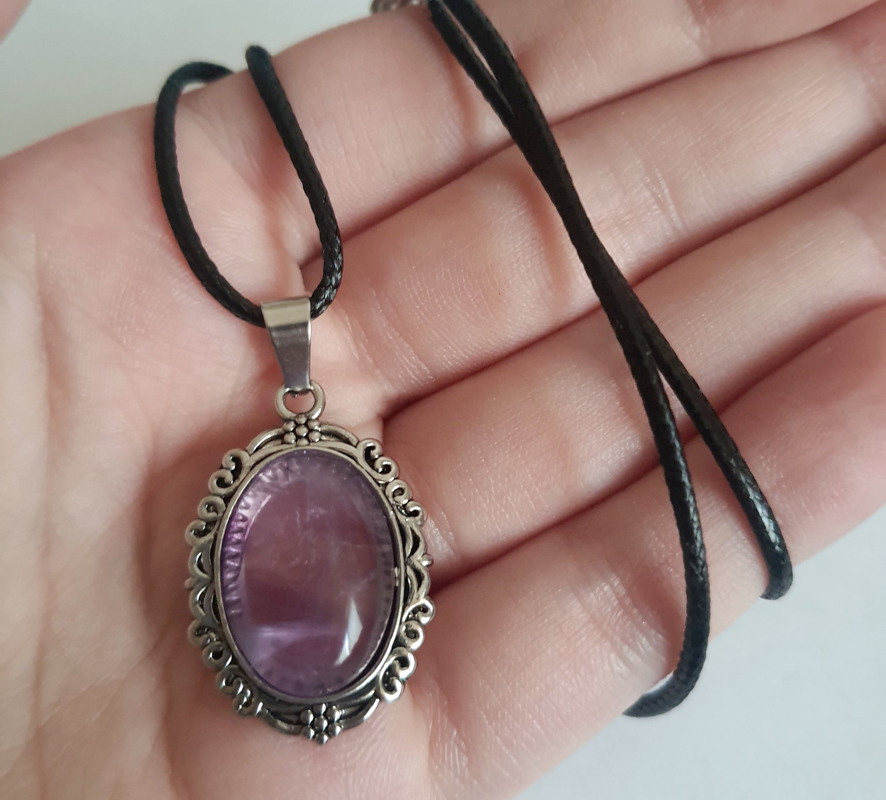 Naszyjnik vintage ze stali nierdzewnej – stal chirurgiczna, wodoodporne, hipoalergiczne, jakość premium. Owalna zawieszka z syntetycznym ametystem w ozdobnej ramie. Czarny rzemyk o długości 40–45 cm. Elegancja i styl RougeBizu.