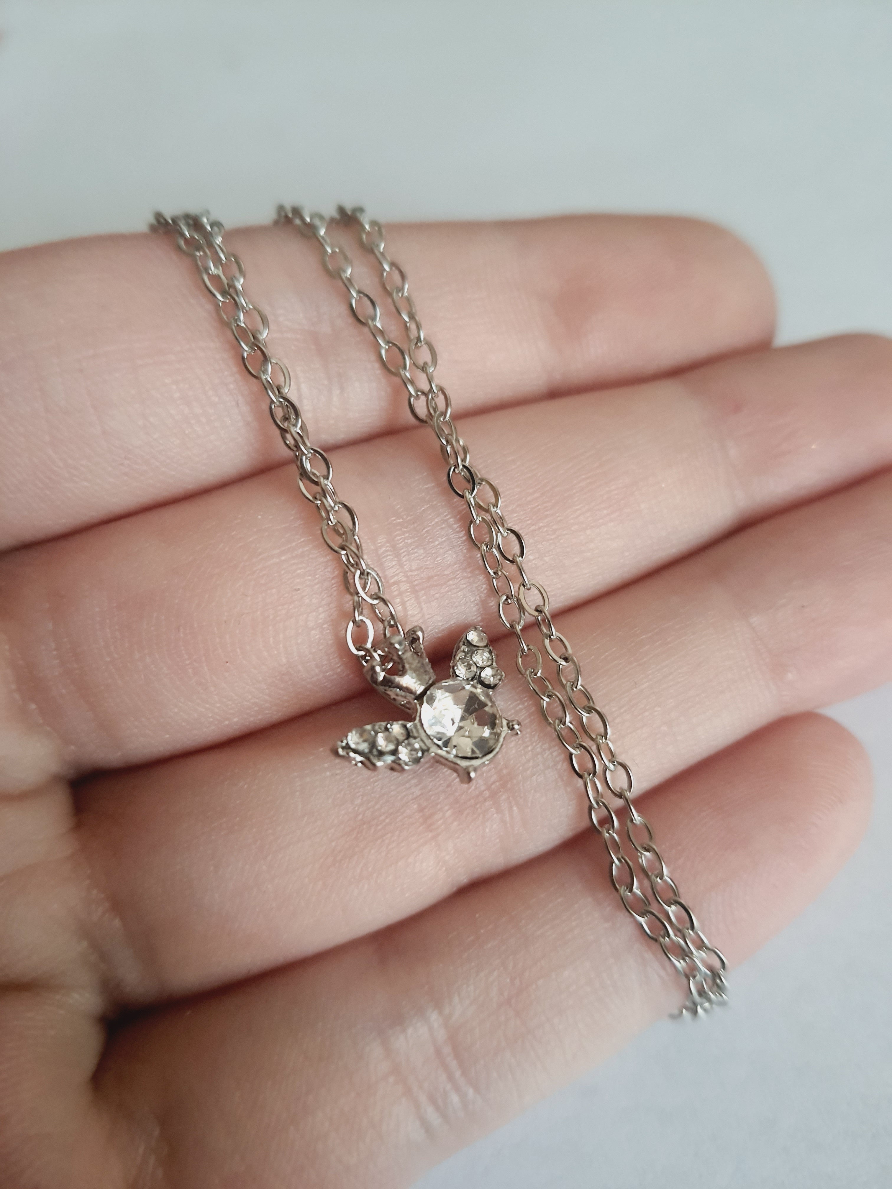 Naszyjnik srebrny ze stali nierdzewnej – stal chirurgiczna, wodoodporny, hipoalergiczny, jakość premium. Zawieszka w kształcie pszczółki z kryształowym środkiem i zdobionymi skrzydełkami. Długość łańcuszka 42–49 cm. Styl RougeBizu.