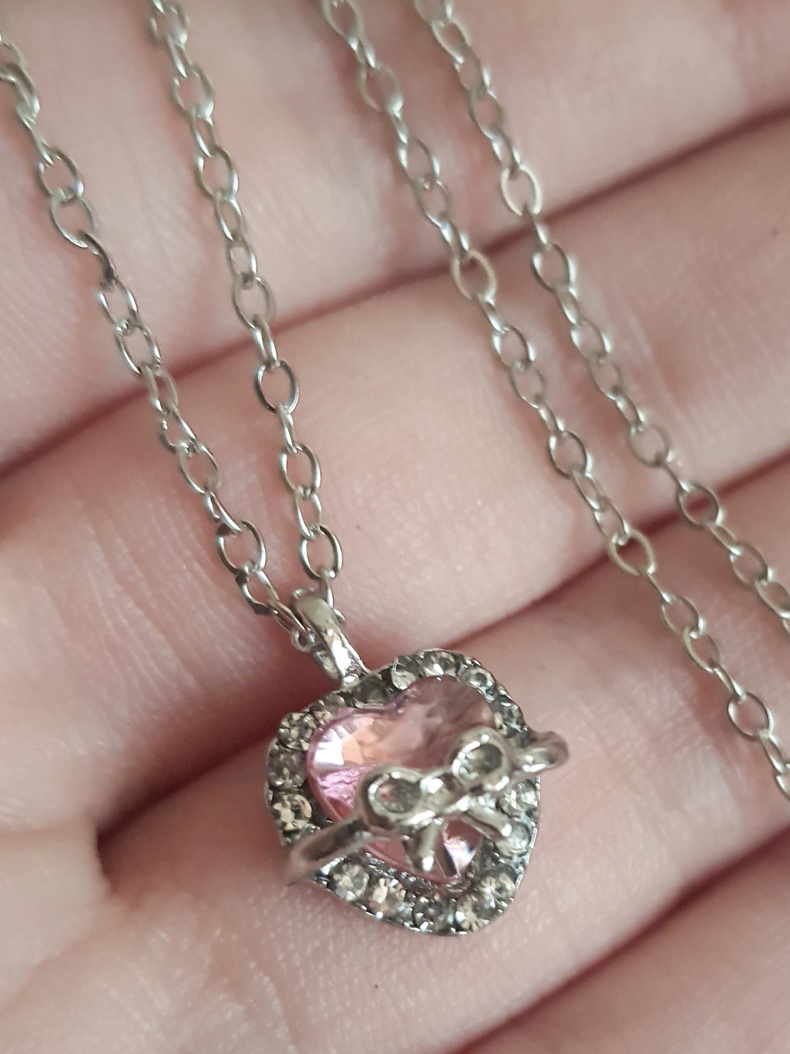 Srebrny naszyjnik ze stali nierdzewnej – stal chirurgiczna, wodoodporny, hipoalergiczny, jakość premium. Zawieszka w kształcie różowego serca z kokardką i otoczką z cyrkonii. Długość łańcuszka 42–49 cm. RougeBizu.