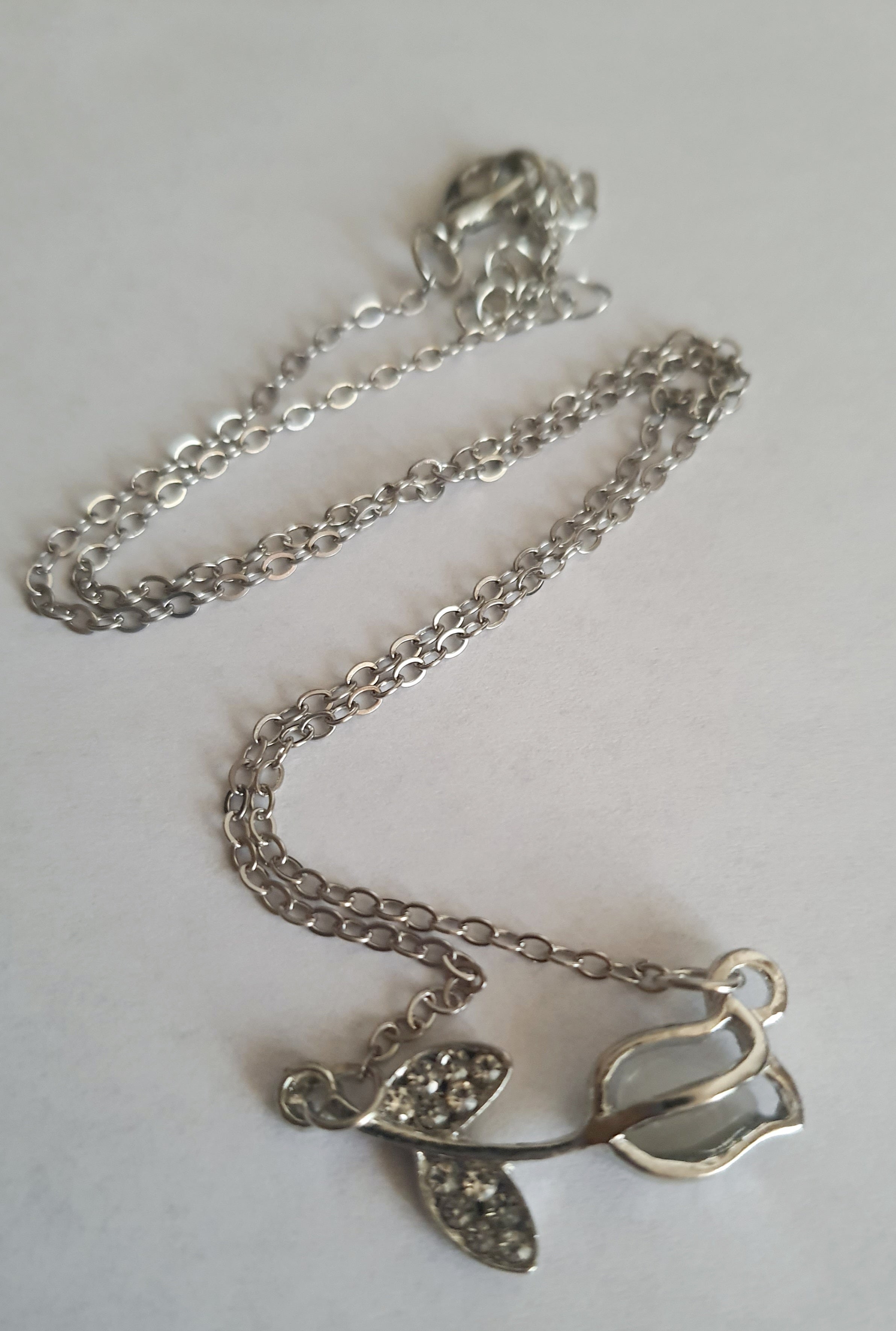 Srebrny naszyjnik ze stali nierdzewnej – stal chirurgiczna, wodoodporny, hipoalergiczny, jakość premium. Zawieszka w kształcie róży z listkami ozdobionymi cyrkoniami. Długość łańcuszka 42–49 cm. RougeBizu.