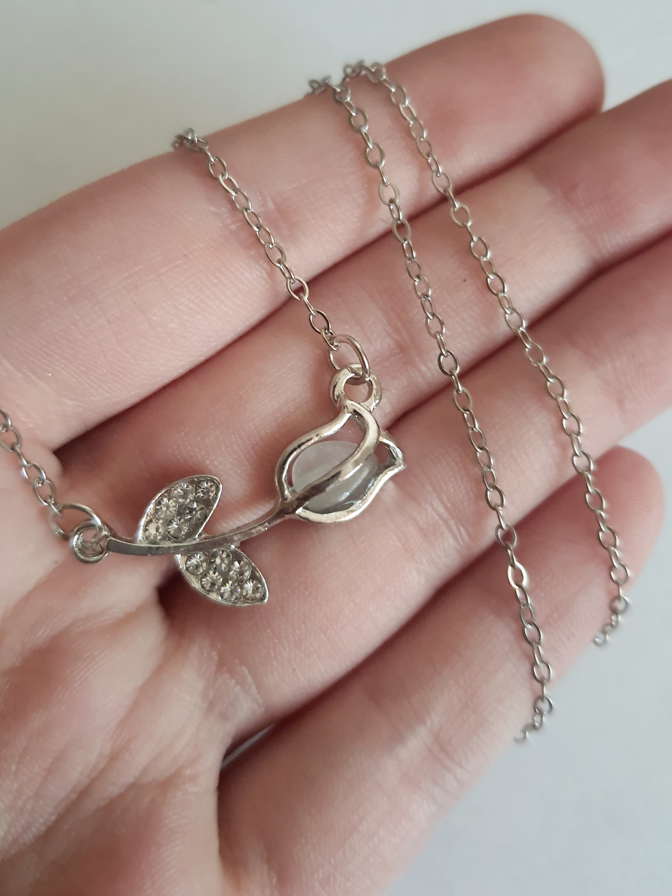 Srebrny naszyjnik ze stali nierdzewnej – stal chirurgiczna, wodoodporny, hipoalergiczny, jakość premium. Zawieszka w kształcie róży z listkami ozdobionymi cyrkoniami. Długość łańcuszka 42–49 cm. RougeBizu.