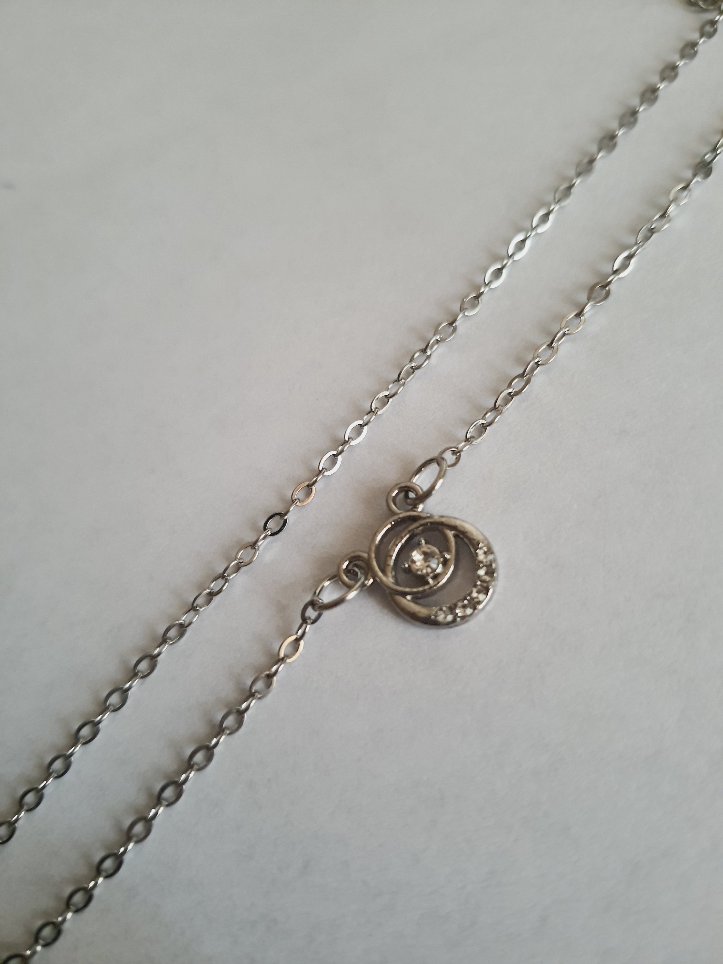 Srebrny naszyjnik ze stali nierdzewnej – stal chirurgiczna, wodoodporny, hipoalergiczny, jakość premium. Zawieszka w kształcie okręgu z centralnym kryształem i drobnymi cyrkoniami. Długość łańcuszka 42–47 cm. RougeBizu.