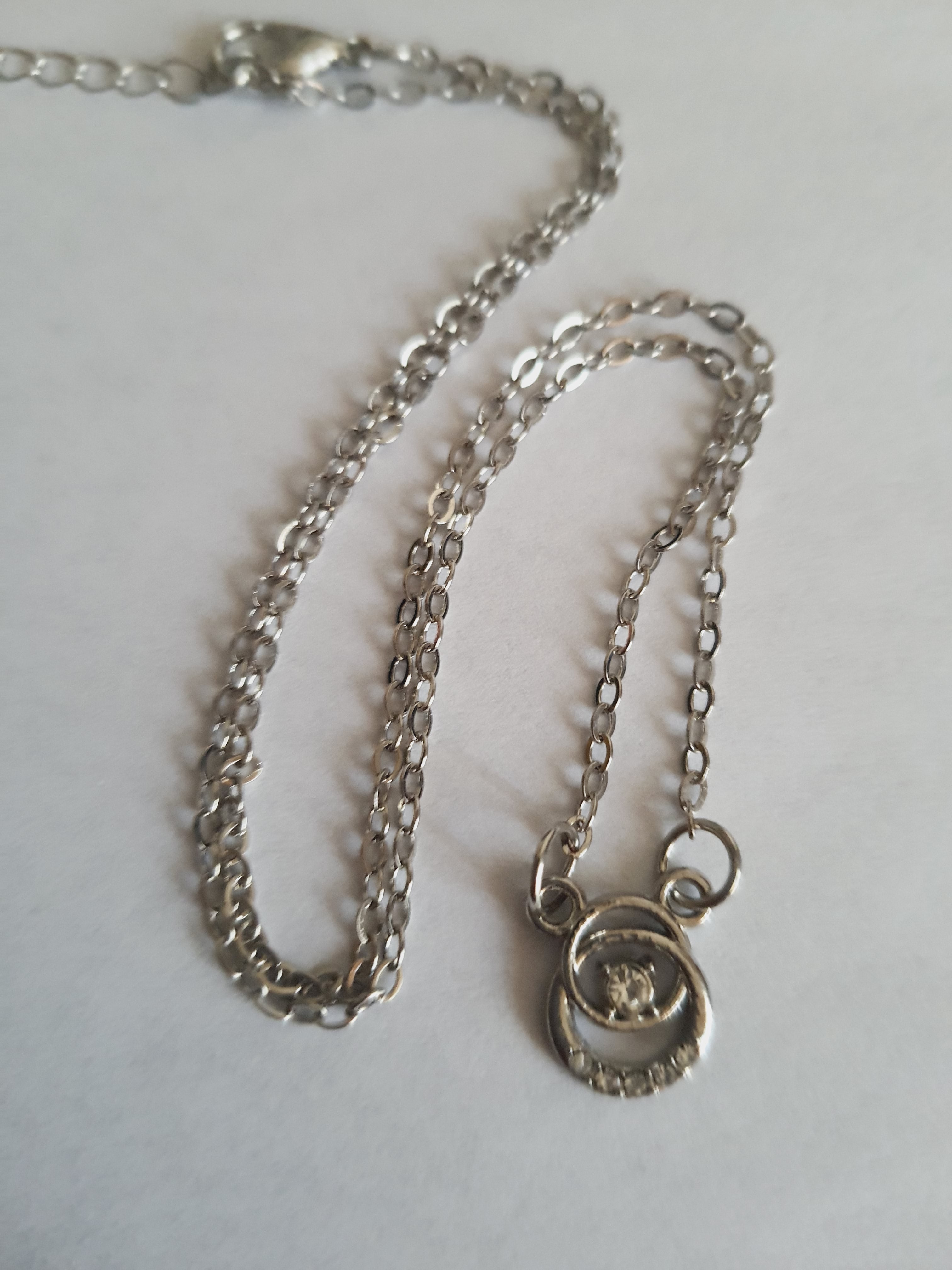 Srebrny naszyjnik ze stali nierdzewnej – stal chirurgiczna, wodoodporny, hipoalergiczny, jakość premium. Zawieszka w kształcie okręgu z centralnym kryształem i drobnymi cyrkoniami. Długość łańcuszka 42–47 cm. RougeBizu.