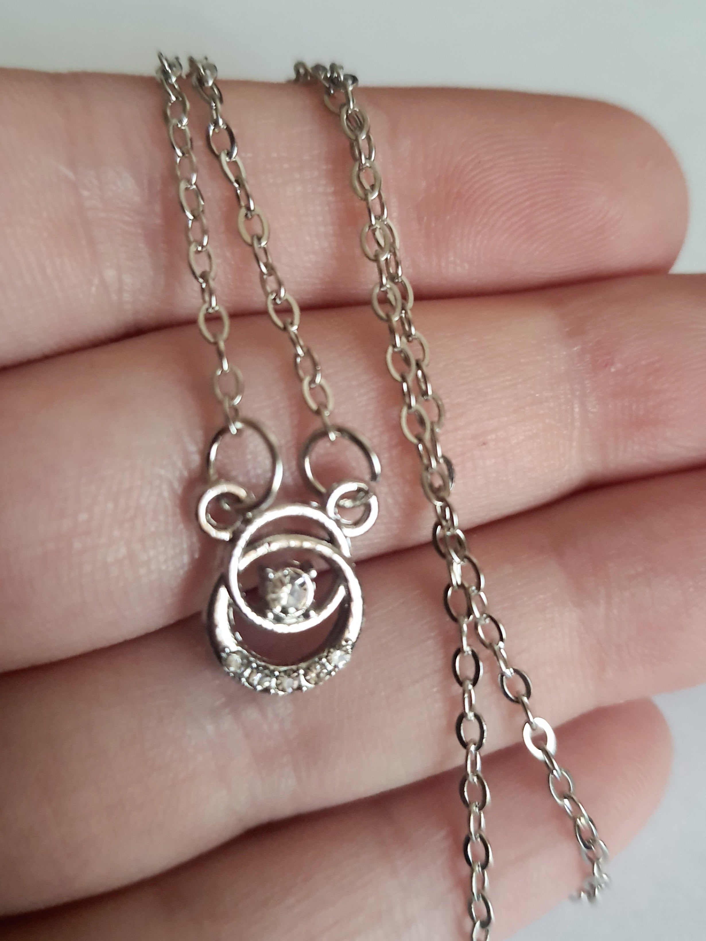 Srebrny naszyjnik ze stali nierdzewnej – stal chirurgiczna, wodoodporny, hipoalergiczny, jakość premium. Zawieszka w kształcie okręgu z centralnym kryształem i drobnymi cyrkoniami. Długość łańcuszka 42–47 cm. RougeBizu.