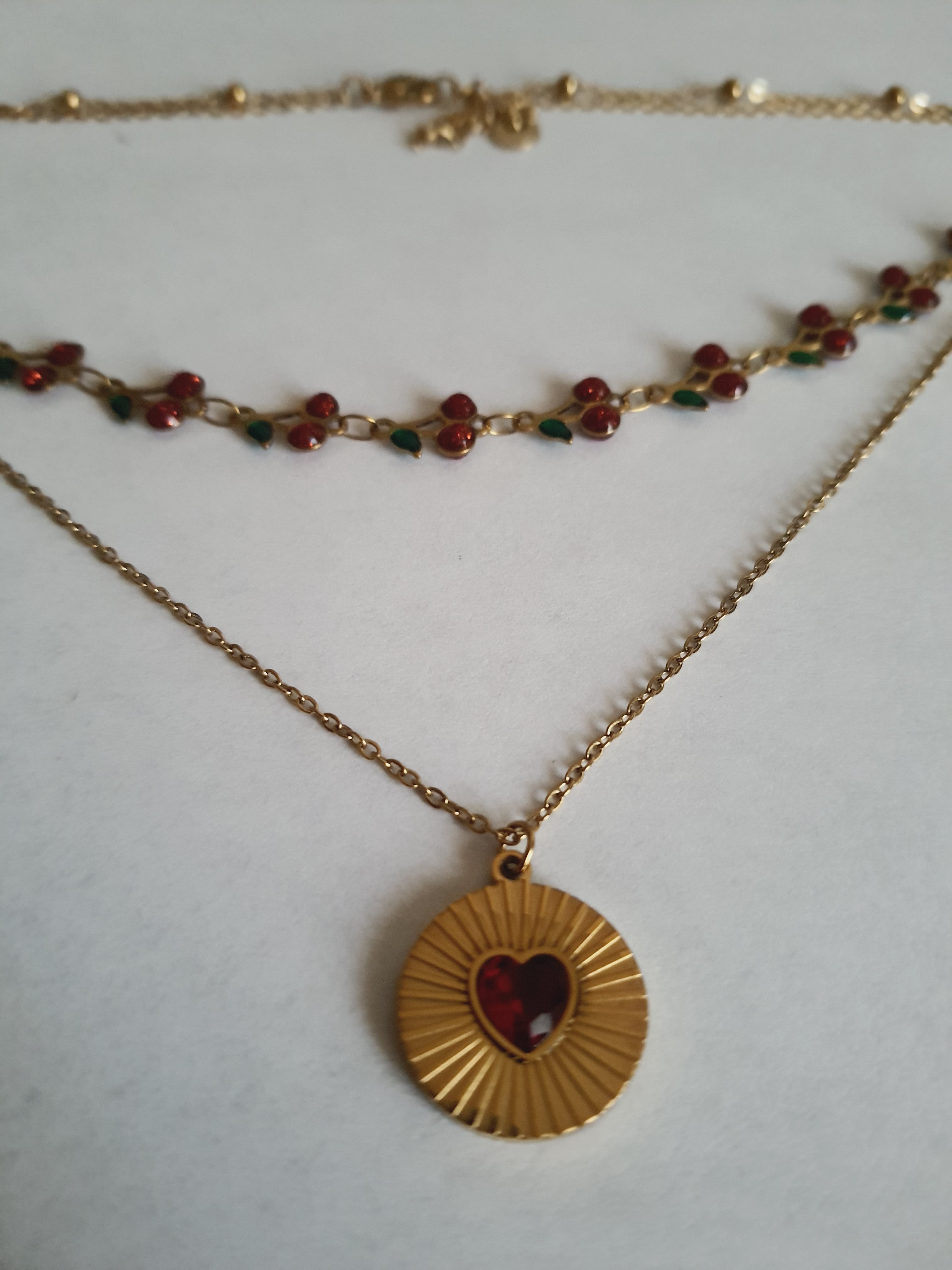 Podwójny złoty naszyjnik ze stali nierdzewnej – stal chirurgiczna, wodoodporny, hipoalergiczny, jakość premium. Pierwsza warstwa z czerwonymi wiśniami i zielonymi listkami, druga z medalionem i czerwonym sercem. Długość 40–50 cm. RougeBizu.