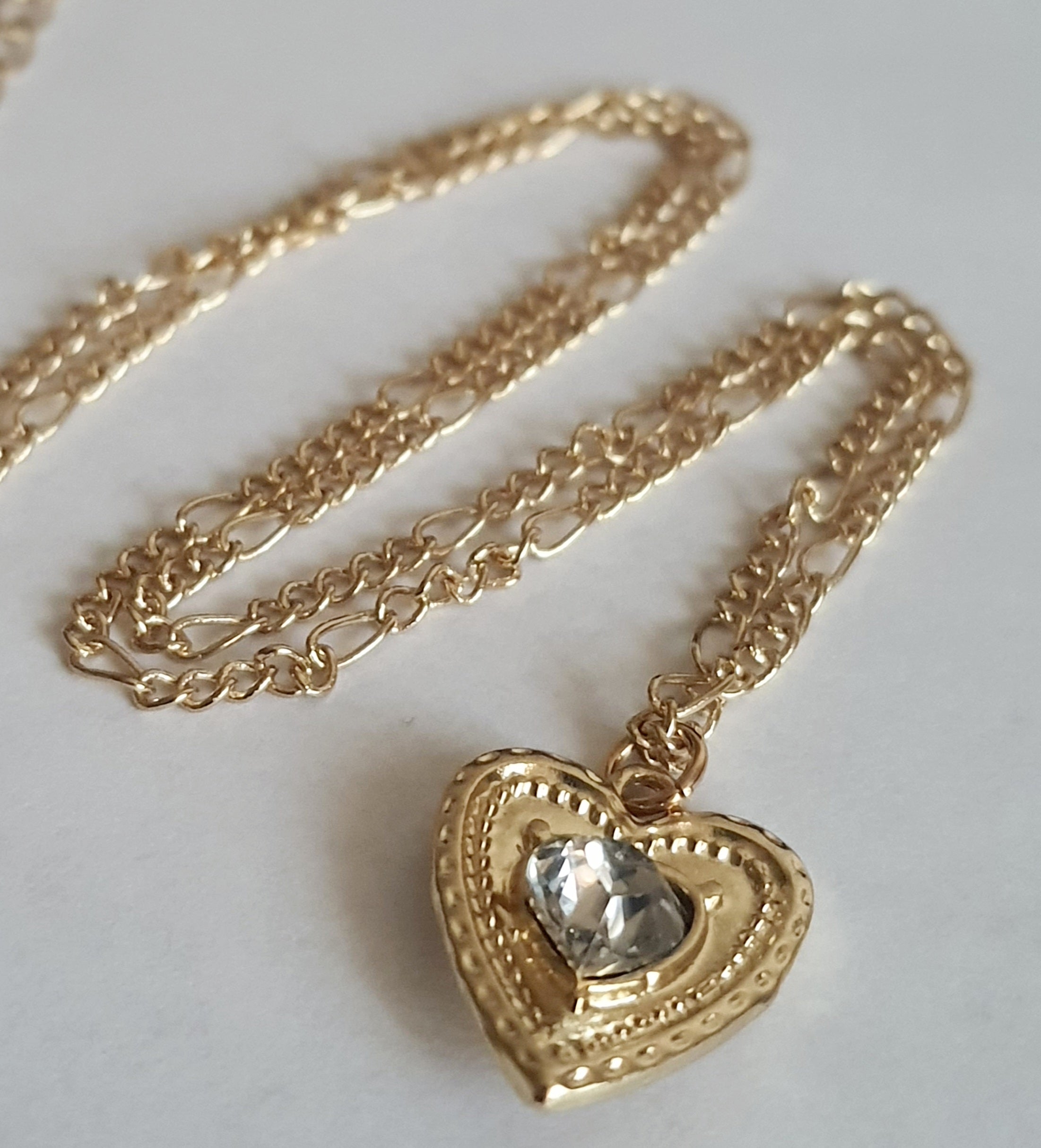 Złoty naszyjnik ze stali chirurgicznej, łańcuszek 43–50 cm, zawieszka w kształcie serca z centralnym kryształem, elegancja i romantyczny styl. Stal nierdzewna, wodoodporne, hipoalergiczne, jakość premium. Rouge Bizu.