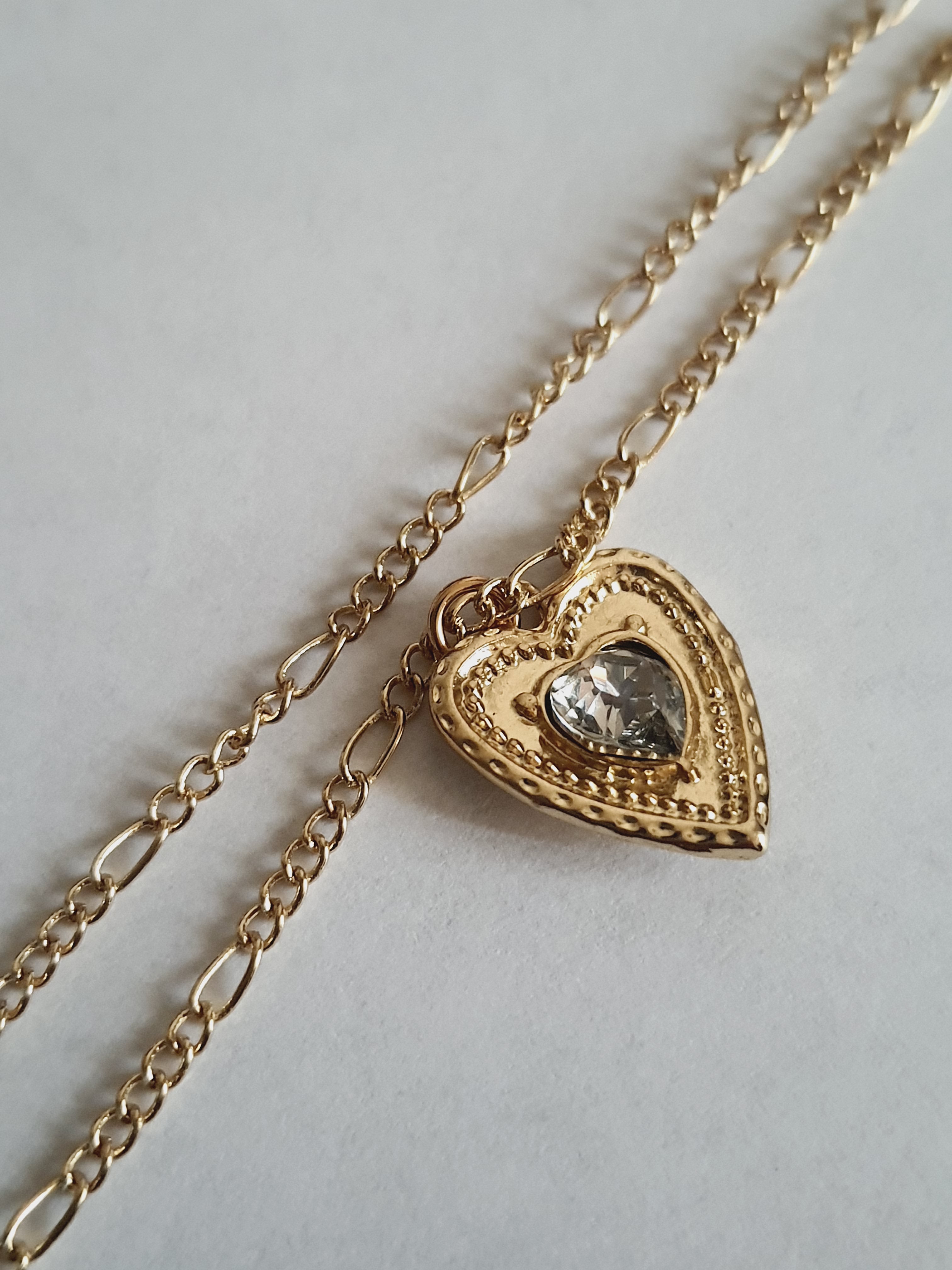 Złoty naszyjnik ze stali chirurgicznej, łańcuszek 43–50 cm, zawieszka w kształcie serca z centralnym kryształem, elegancja i romantyczny styl. Stal nierdzewna, wodoodporne, hipoalergiczne, jakość premium. Rouge Bizu.