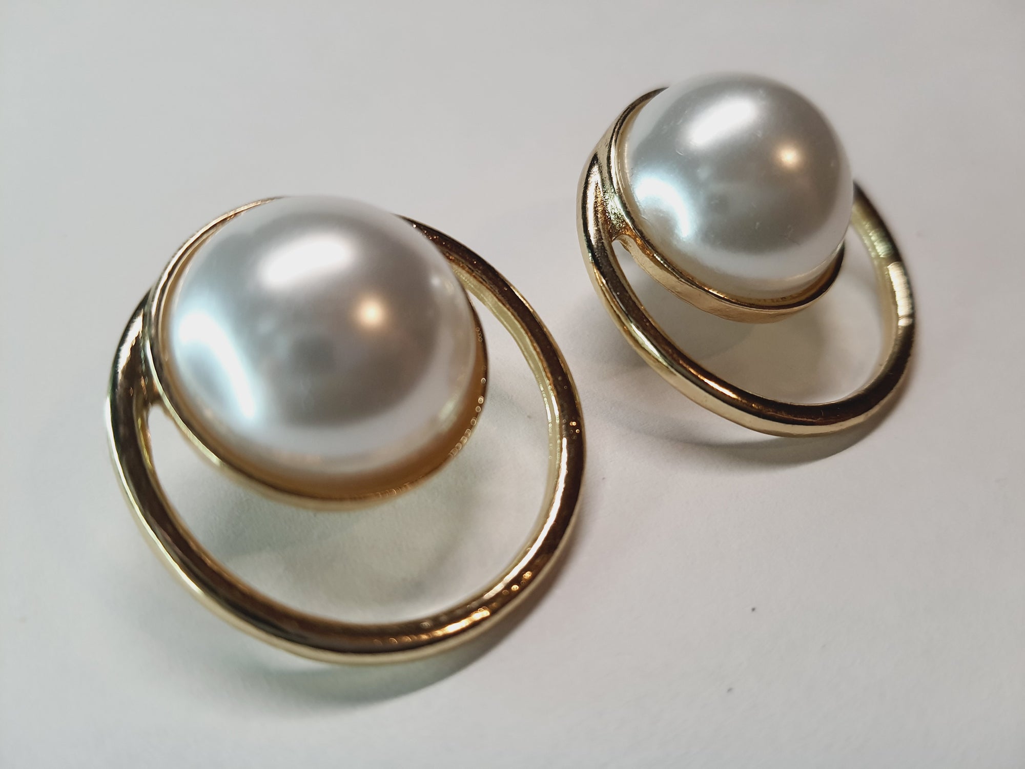 Kolczyki w złotej oprawie z dużą białą perłą w centrum i minimalistycznym okręgiem, średnica 3 cm, styl nowoczesny glamour. Stal nierdzewna, stal chirurgiczna, wodoodporne, hipoalergiczne, jakość premium, RougeBizu.
