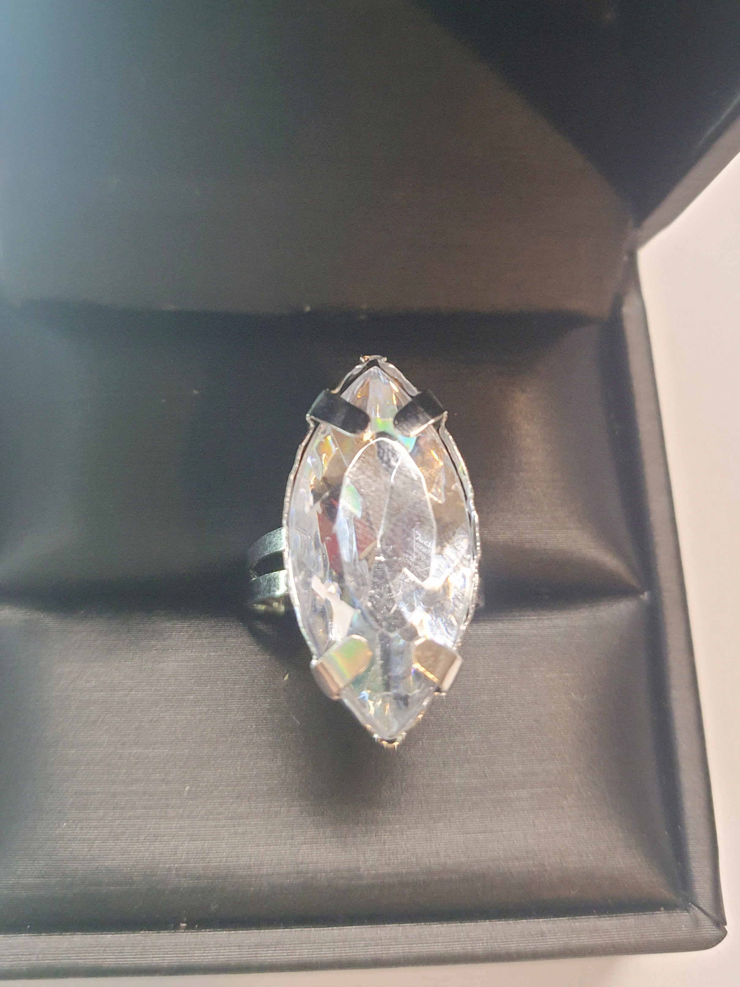 Srebrny pierścionek z dużym transparentnym kamieniem w kształcie łezki, metal, szlifowany kamień o lśniącym połysku, styl glamour, regulowany rozmiar, Rouge Bizu.