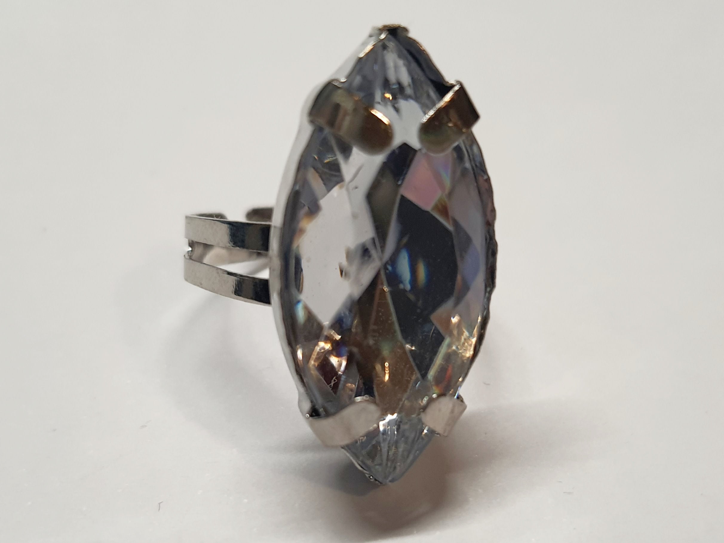 Srebrny pierścionek z dużym transparentnym kamieniem w kształcie łezki, metal, szlifowany kamień o lśniącym połysku, styl glamour, regulowany rozmiar, Rouge Bizu.