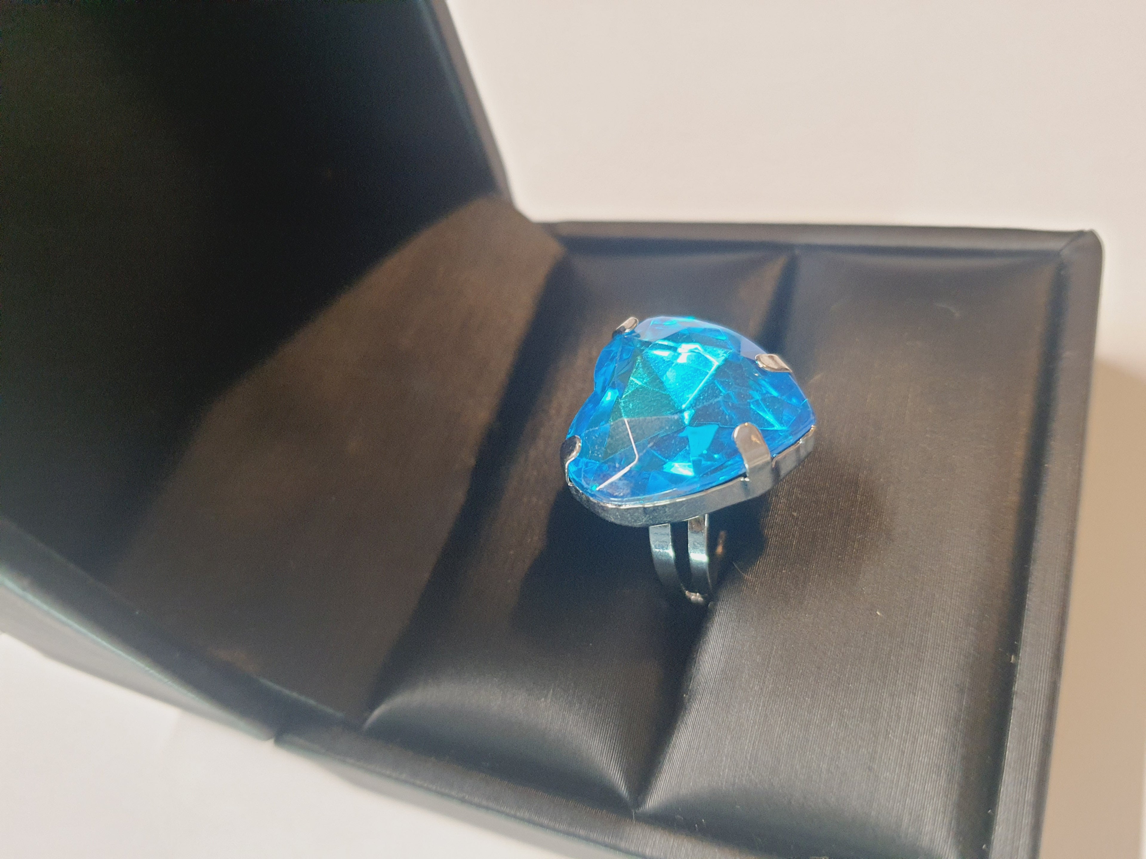 Srebrny pierścionek z dużym niebieskim kamieniem w kształcie serca, metal, szlifowany kamień o morskim odcieniu, styl romantyczny glamour, regulowany rozmiar, Rouge Bizu.