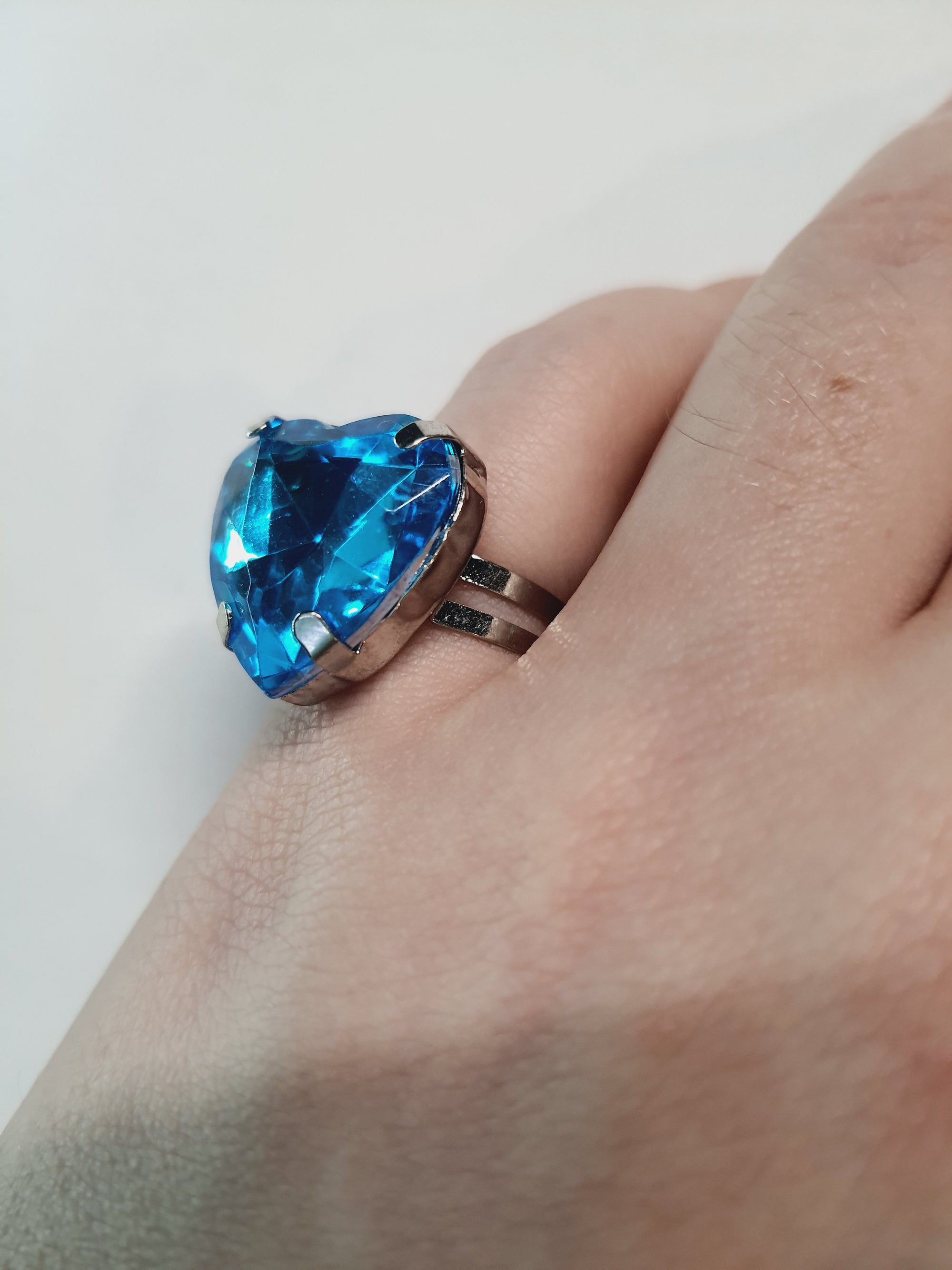 Srebrny pierścionek z dużym niebieskim kamieniem w kształcie serca, metal, szlifowany kamień o morskim odcieniu, styl romantyczny glamour, regulowany rozmiar, Rouge Bizu.