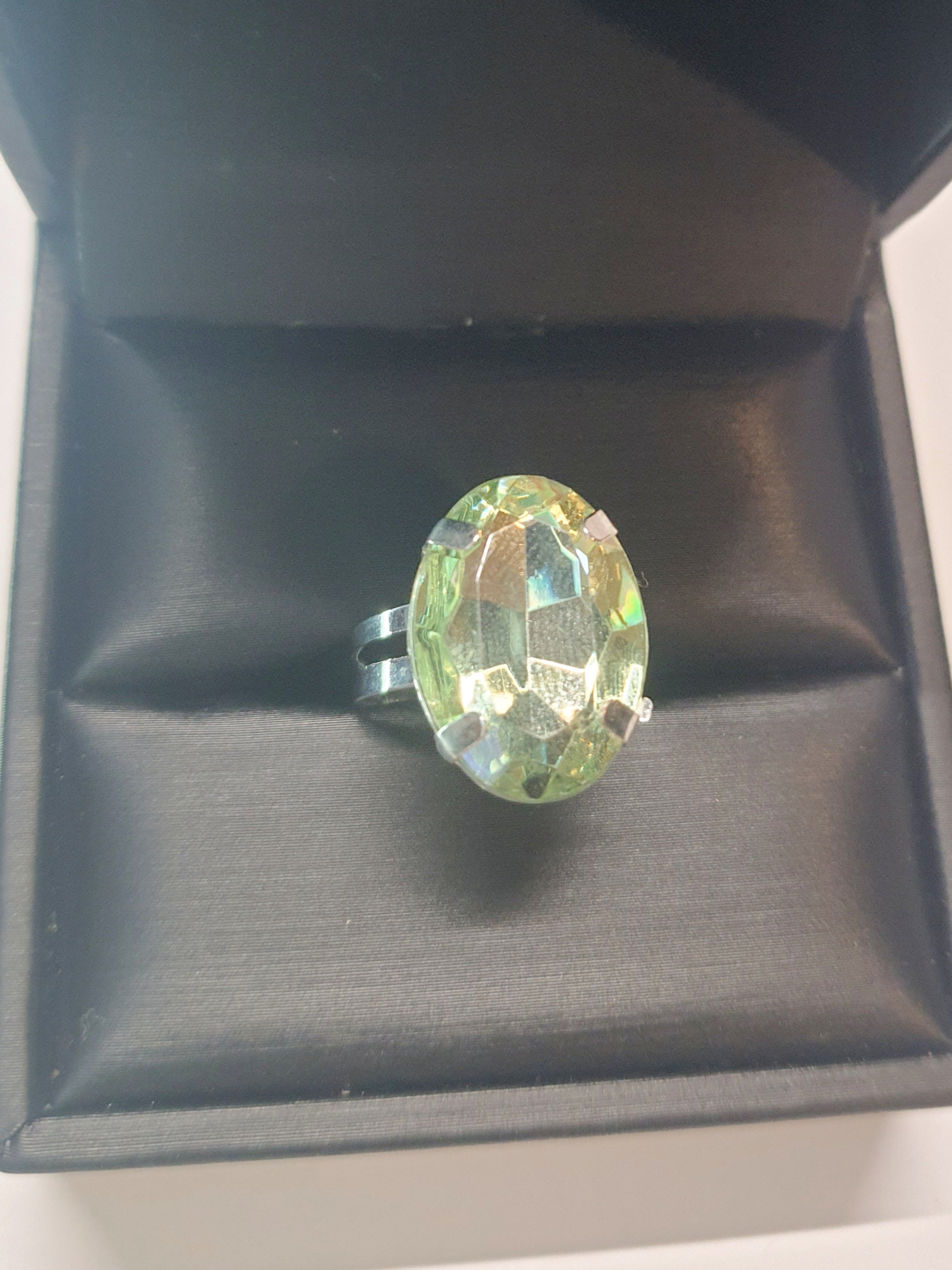 Srebrny pierścionek z dużym oliwkowo-zielonym owalnym kamieniem, metal, elegancki styl, szlifowany kamień o subtelnym połysku, regulowany rozmiar, Rouge Bizu.