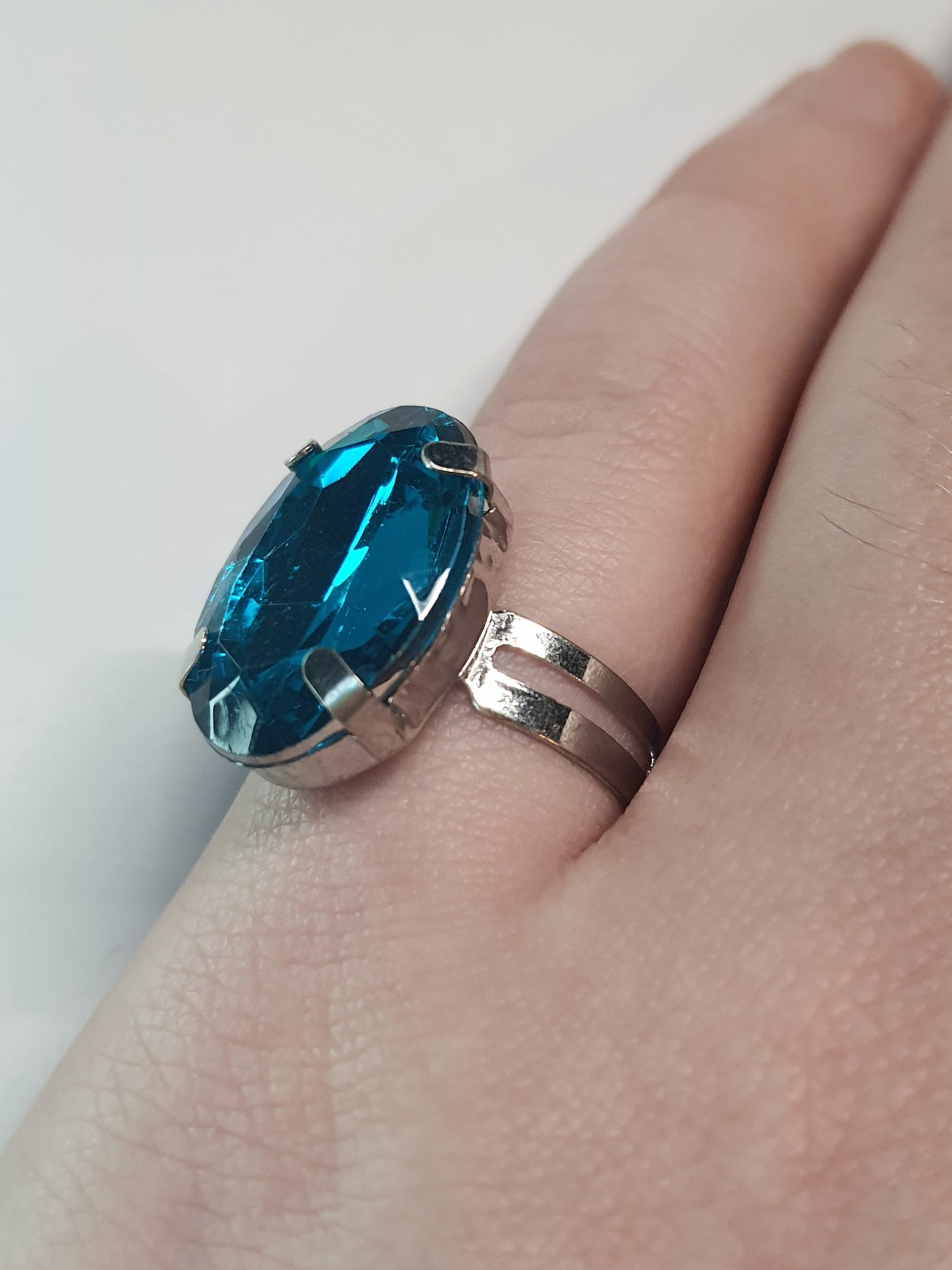 Srebrny pierścionek z dużym granatowo-niebieskim owalnym kamieniem, metal, szlifowany kamień o głębokim blasku, elegancki styl, regulowany rozmiar, Rouge Bizu.