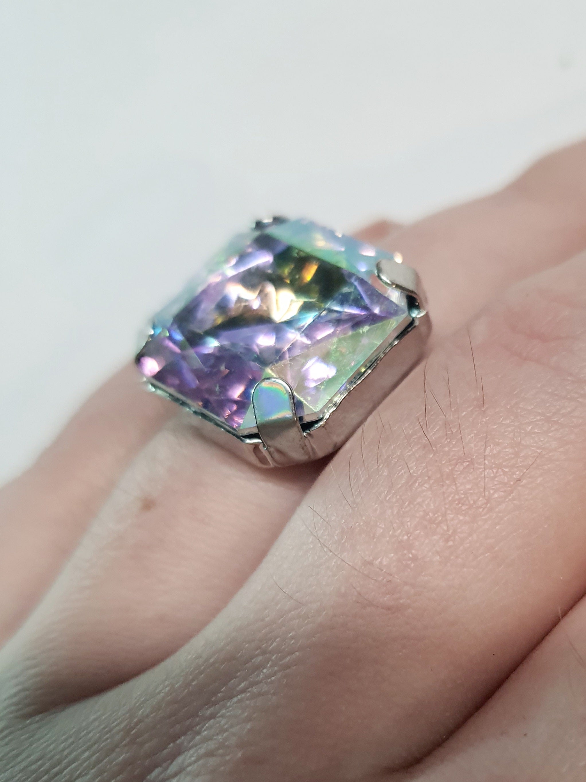 Srebrny pierścionek z dużym wielokolorowym prostokątnym kamieniem, metal, szlifowany kamień o tęczowym połysku, styl glamour, regulowany rozmiar, Rouge Bizu.