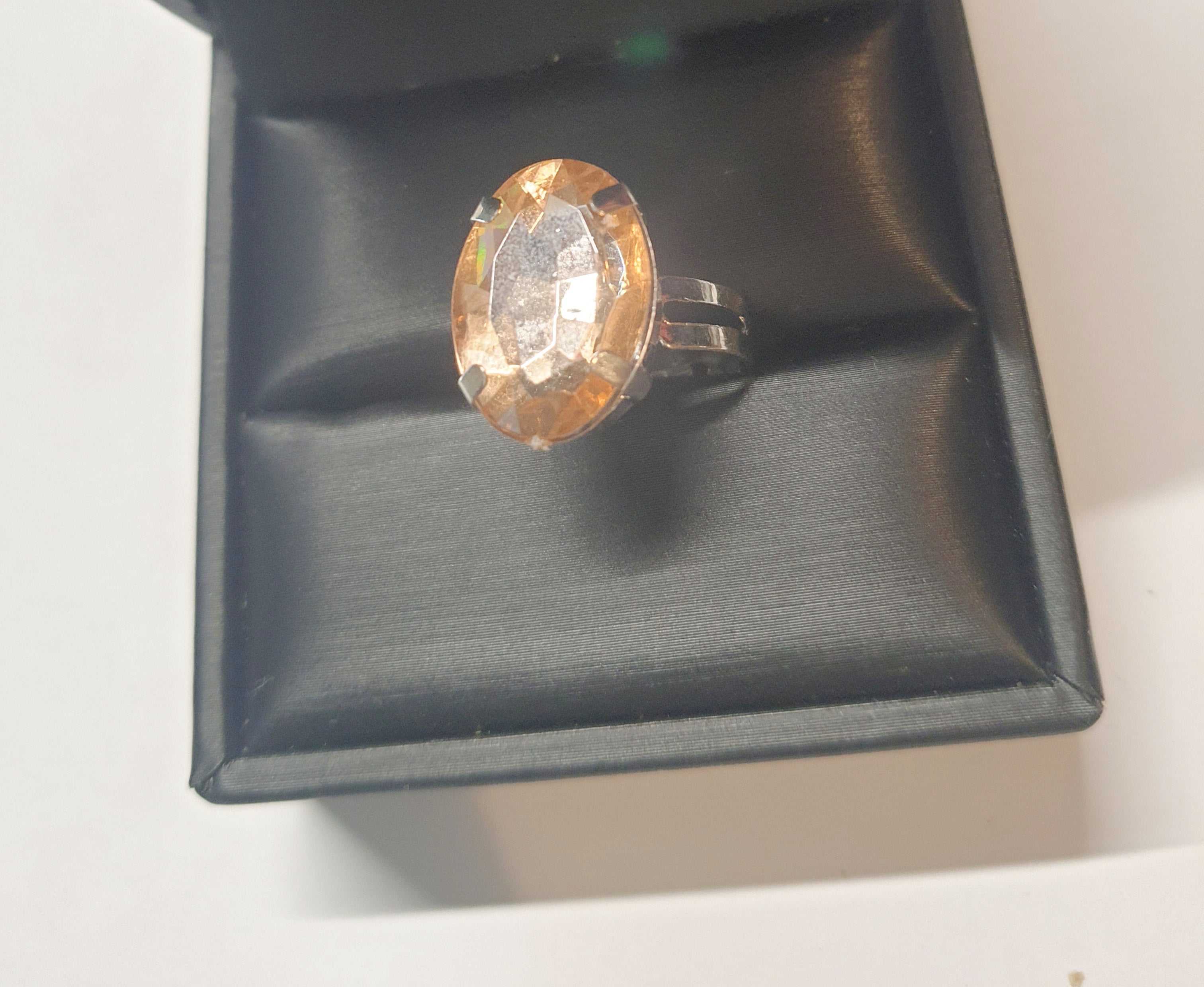 Srebrny pierścionek z dużym bursztynowo-złotym kamieniem o eleganckim szlifie. Regulowany rozmiar, klasyczny styl i ciepły blask. Rouge Bizu.