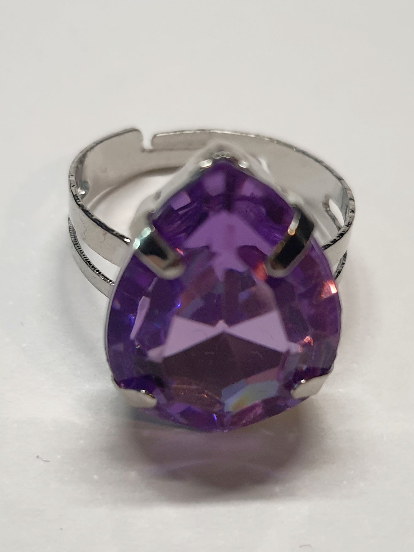 Srebrny pierścionek z dużym fioletowym kamieniem w kształcie łezki, metal, szlifowany kamień o głębokim połysku, elegancki styl, regulowany rozmiar, Rouge Bizu.