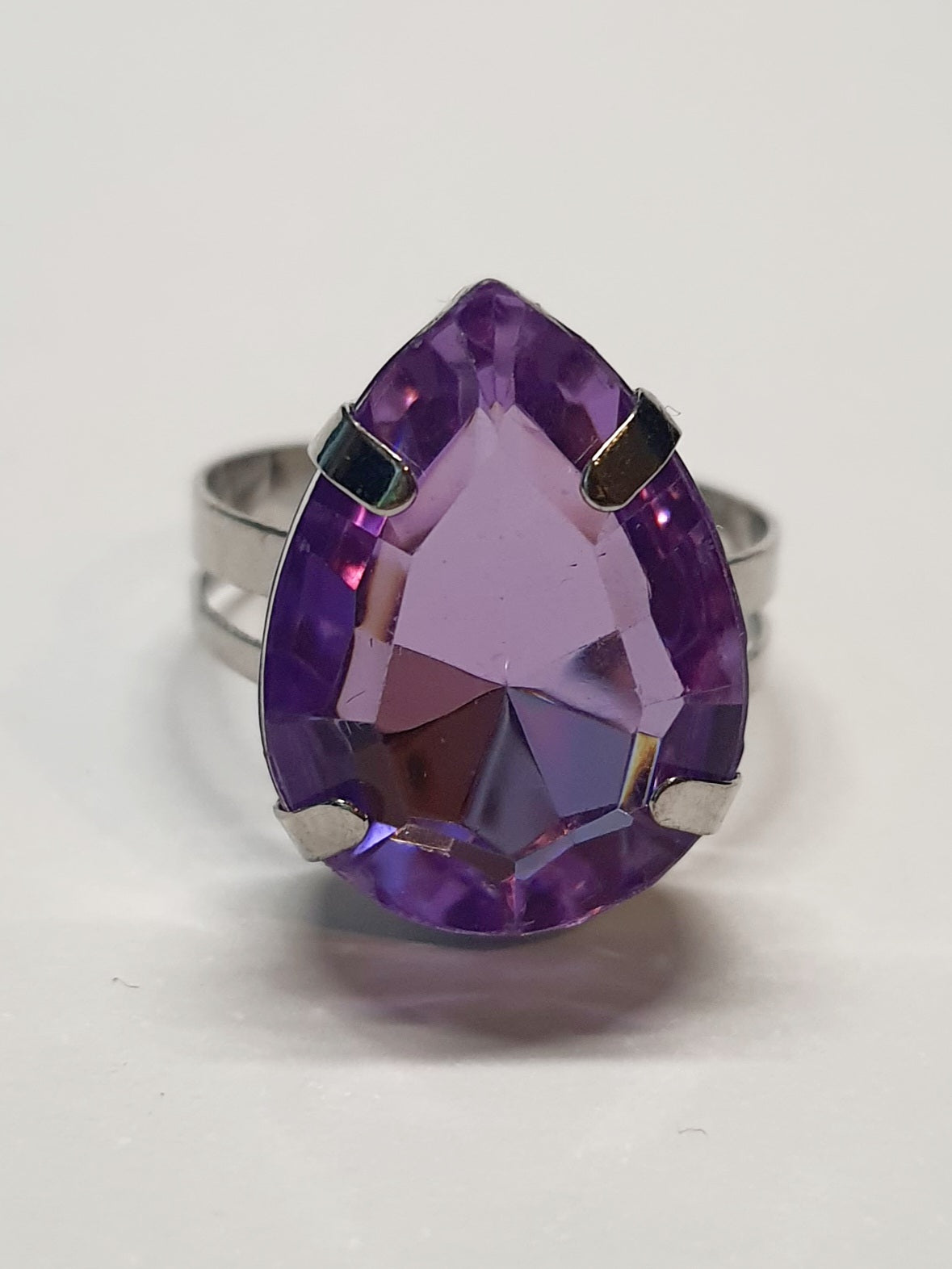Srebrny pierścionek z dużym fioletowym kamieniem w kształcie łezki, metal, szlifowany kamień o głębokim połysku, elegancki styl, regulowany rozmiar, Rouge Bizu.