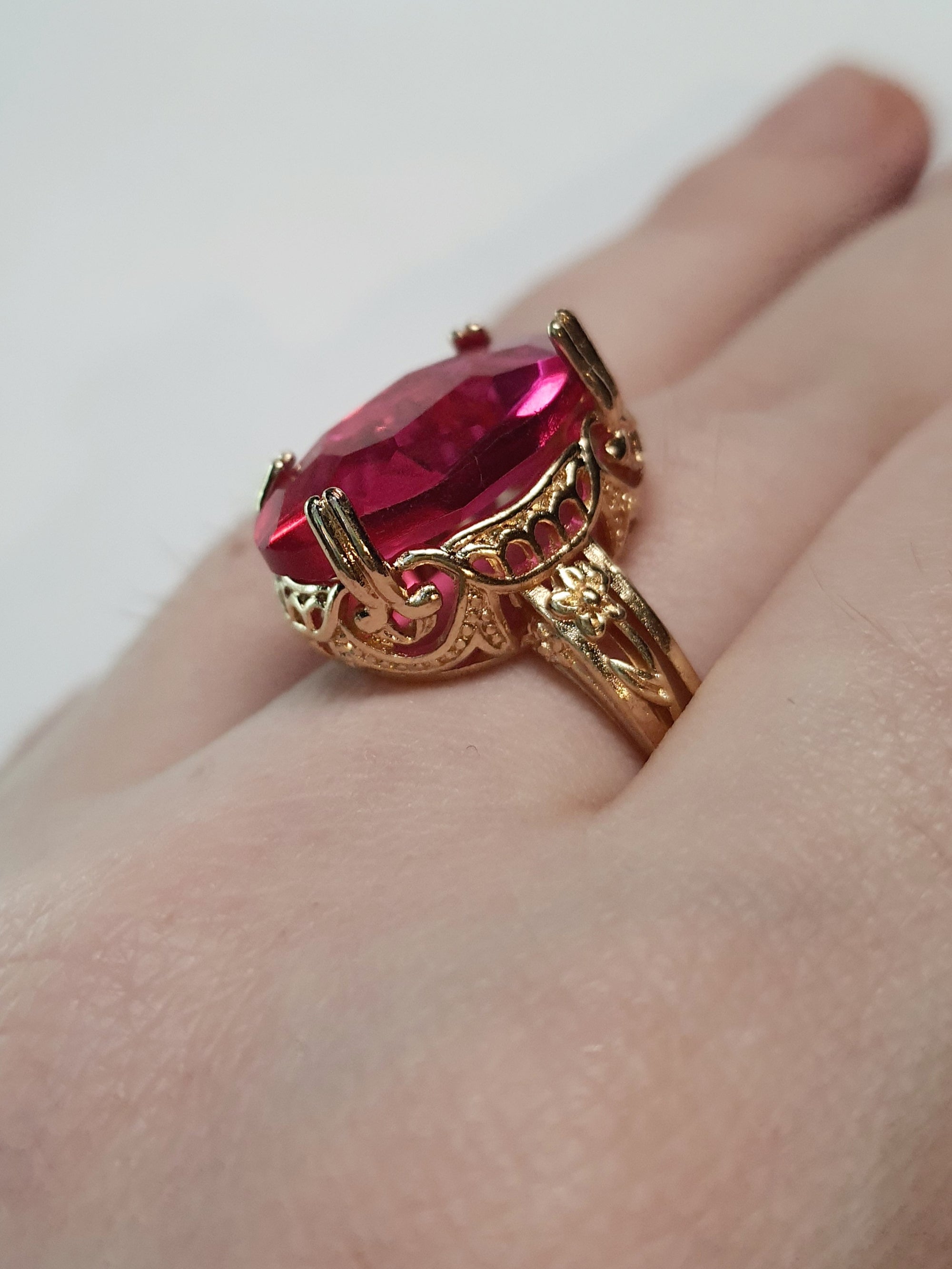 Złoty pierścionek z dużym rubinowym kamieniem w stylu vintage, bogato zdobiony, elegancki i kobiecy. Rozmiar 20 mm. Stal nierdzewna, stal chirurgiczna, wodoodporne, hipoalergiczne, jakość premium. Rouge Bizu.