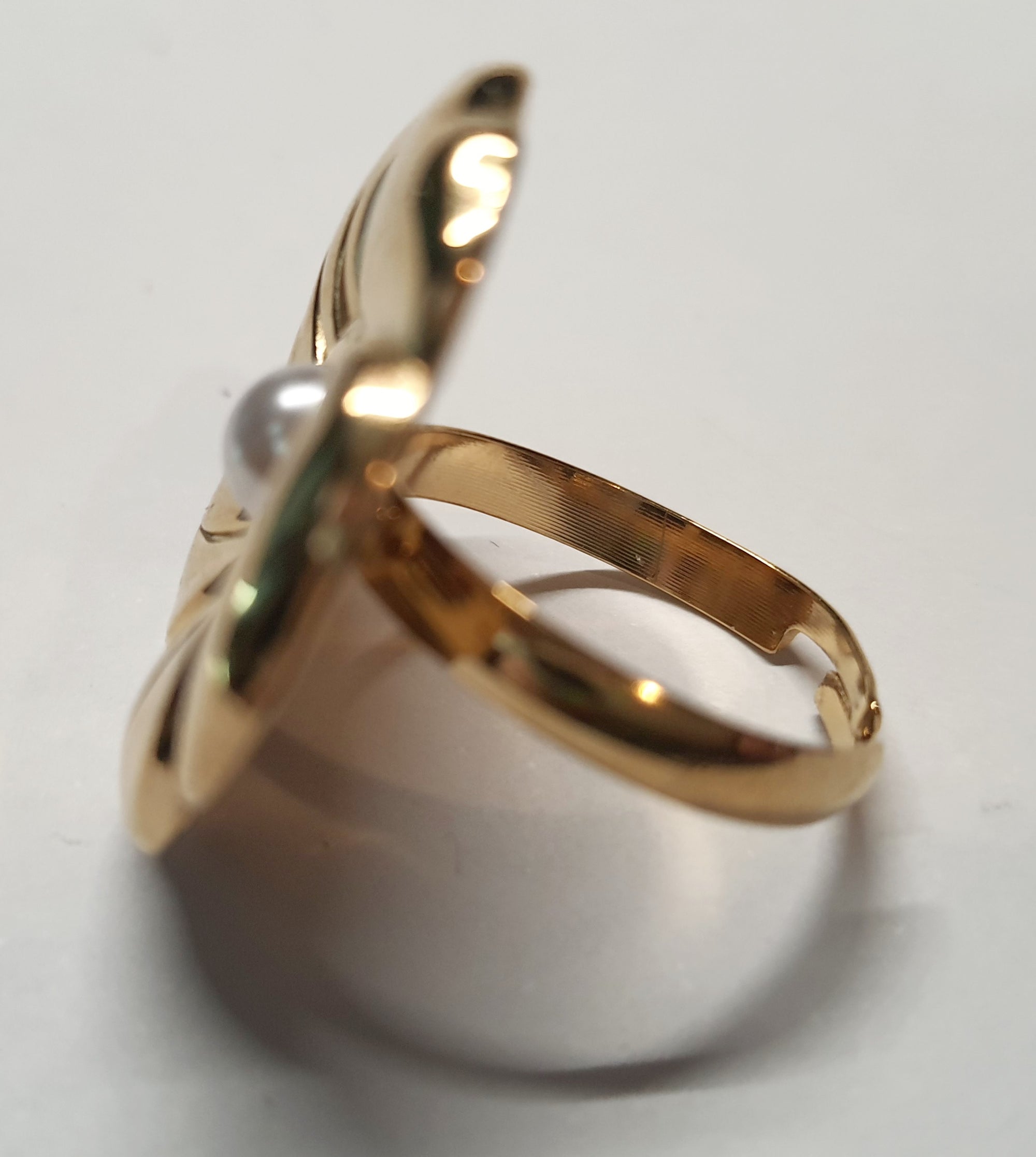 Złoty pierścionek w kształcie kwiatu z białą perłą, kobiecy i elegancki. Rozmiar 17 mm, regulowany. Stal nierdzewna, stal chirurgiczna, wodoodporne, hipoalergiczne, jakość premium. Rouge Bizu.