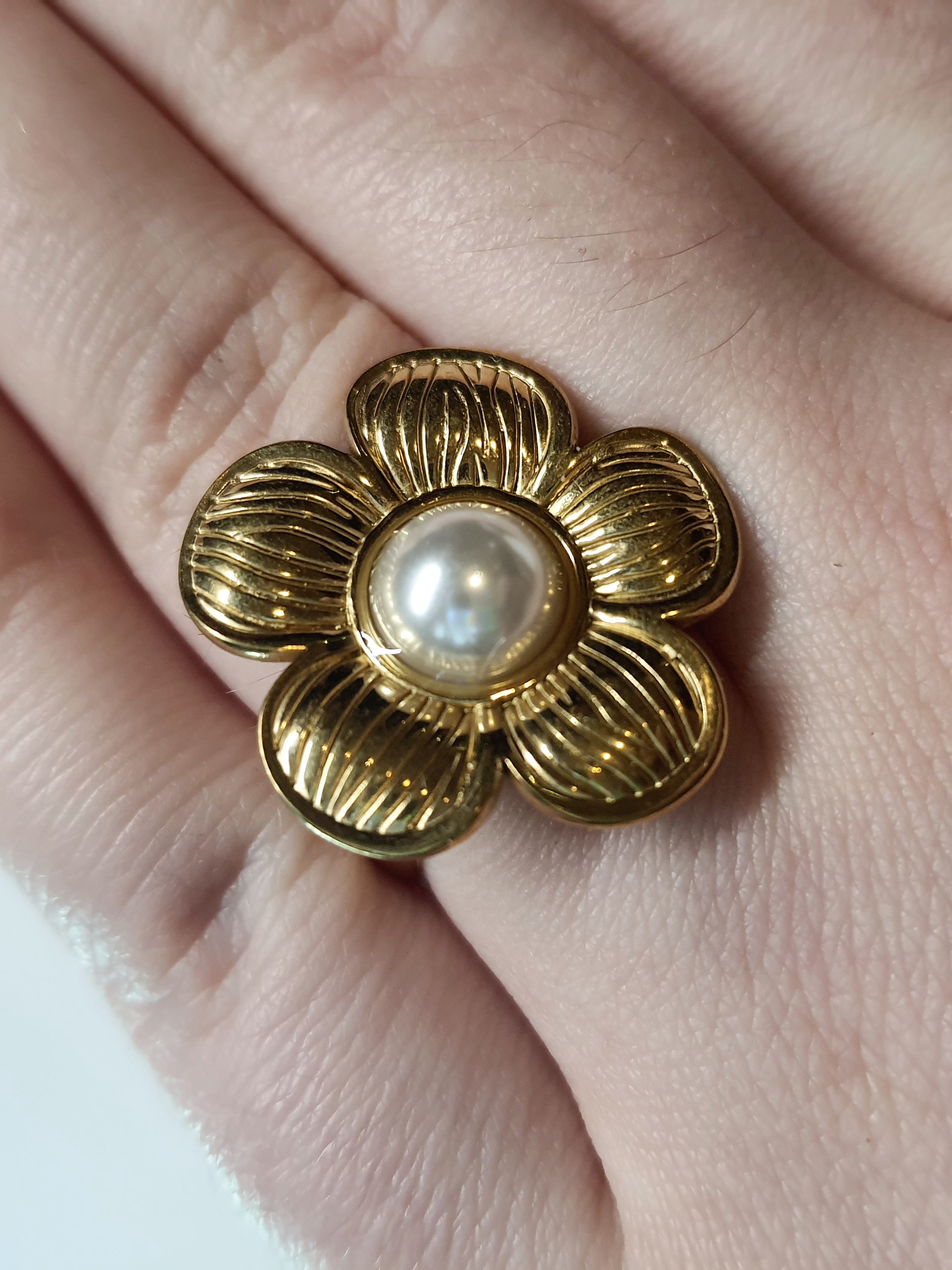 Złoty pierścionek w kształcie kwiatu z białą perłą w centrum, elegancki i kobiecy. Rozmiar 17 mm, regulowany. Stal nierdzewna, stal chirurgiczna, wodoodporne, hipoalergiczne, jakość premium. Rouge Bizu.