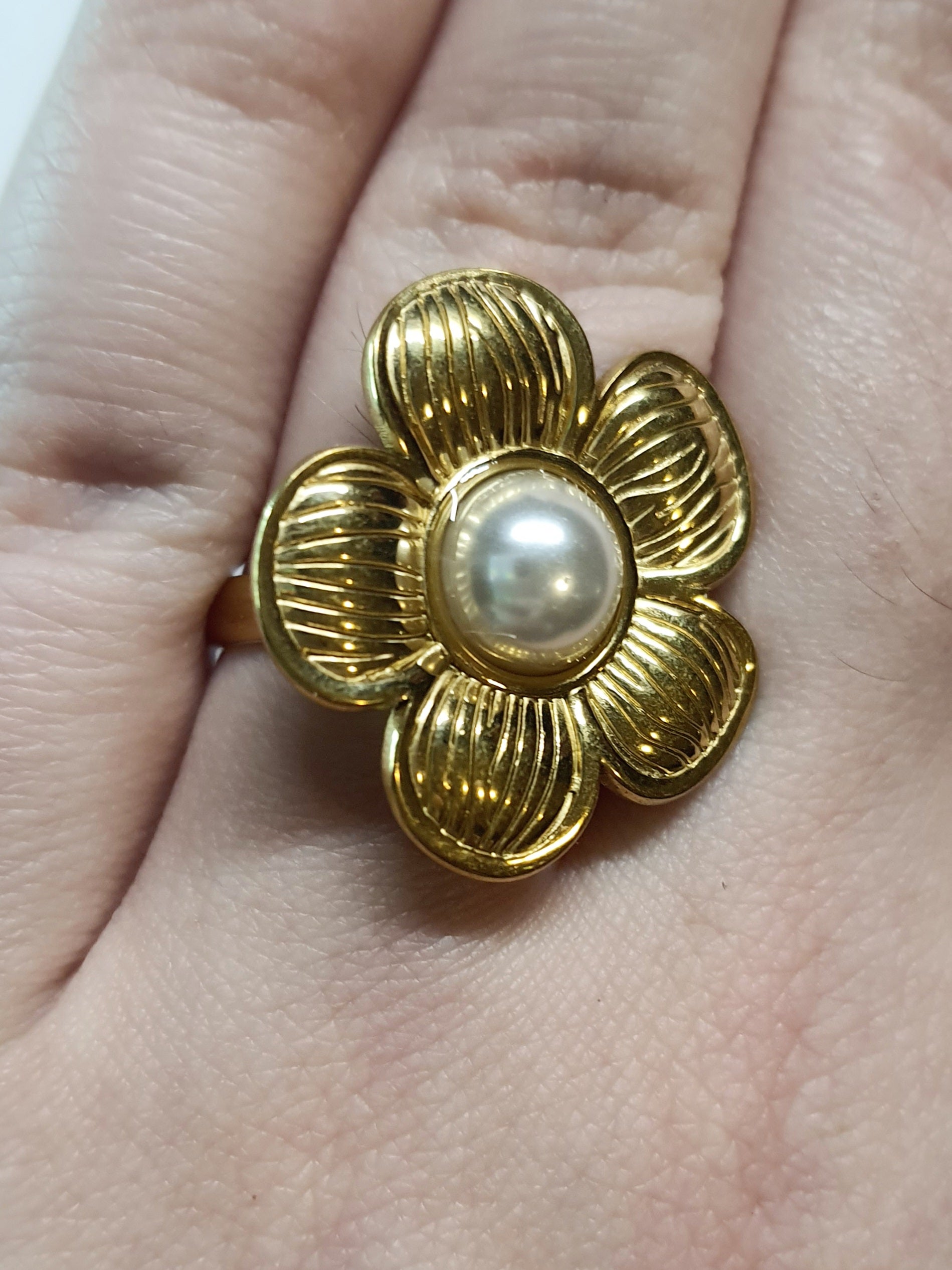 Złoty pierścionek w kształcie kwiatu z białą perłą w centrum, elegancki i kobiecy. Rozmiar 17 mm, regulowany. Stal nierdzewna, stal chirurgiczna, wodoodporne, hipoalergiczne, jakość premium. Rouge Bizu.