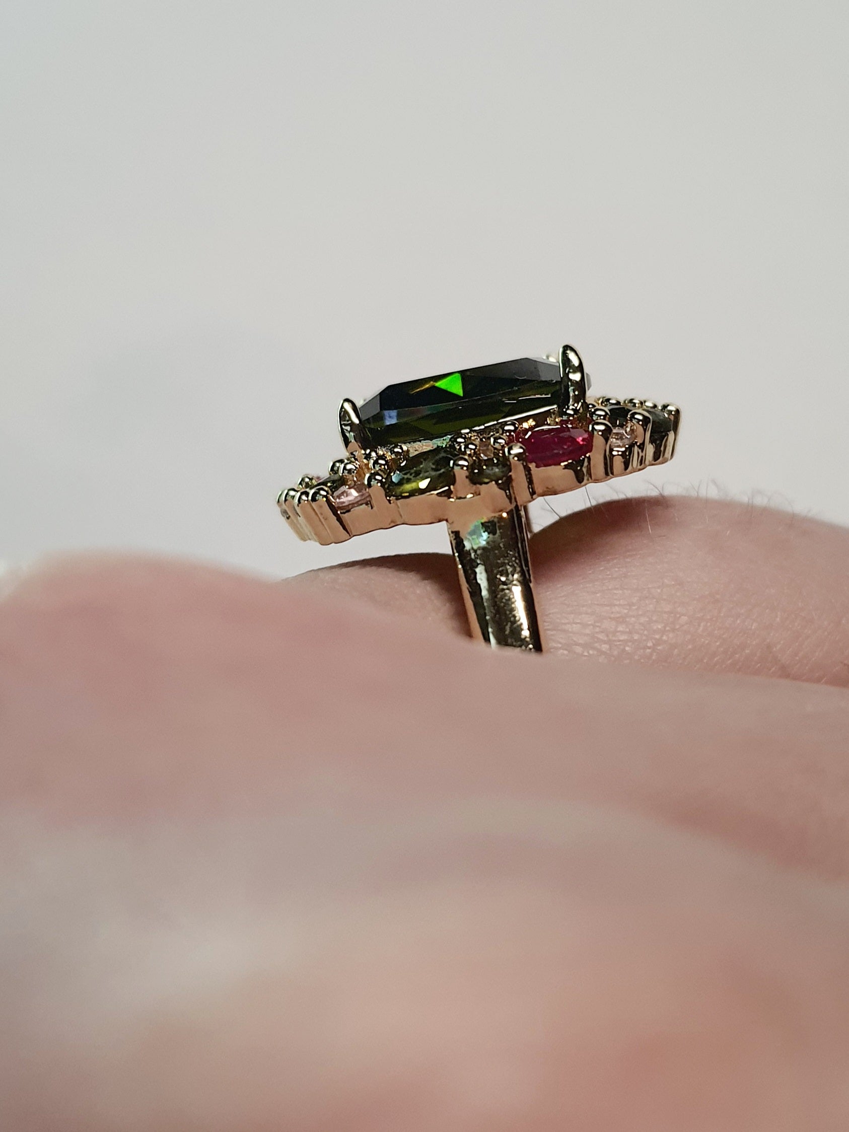 Złoty pierścionek ze stali nierdzewnej z dużym zielonym kamieniem otoczonym kolorowymi kryształami w stylu glamour królewskim. Rozmiar 20 mm. stal chirurgiczna, stal nierdzewna, wodoodporne, hipoalergiczne, jakość premium, RougeBizu.