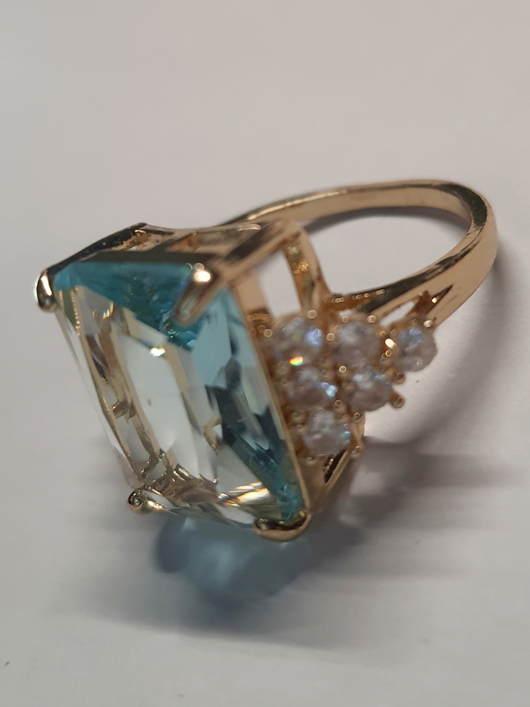 Złoty pierścionek ze stali nierdzewnej z prostokątnym błękitnym kamieniem i cyrkoniami po bokach w stylu glamour klasycznym. Rozmiar 20 mm. stal chirurgiczna, stal nierdzewna, wodoodporne, hipoalergiczne, jakość premium, RougeBizu.