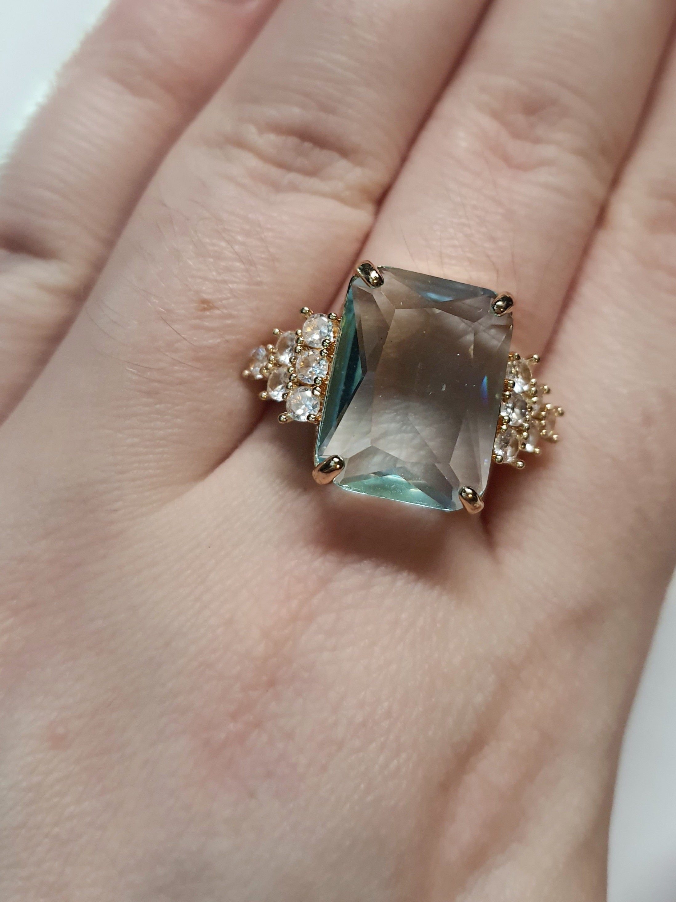 Złoty pierścionek ze stali nierdzewnej z prostokątnym błękitnym kamieniem i cyrkoniami po bokach w stylu glamour klasycznym. Rozmiar 20 mm. stal chirurgiczna, stal nierdzewna, wodoodporne, hipoalergiczne, jakość premium, RougeBizu.